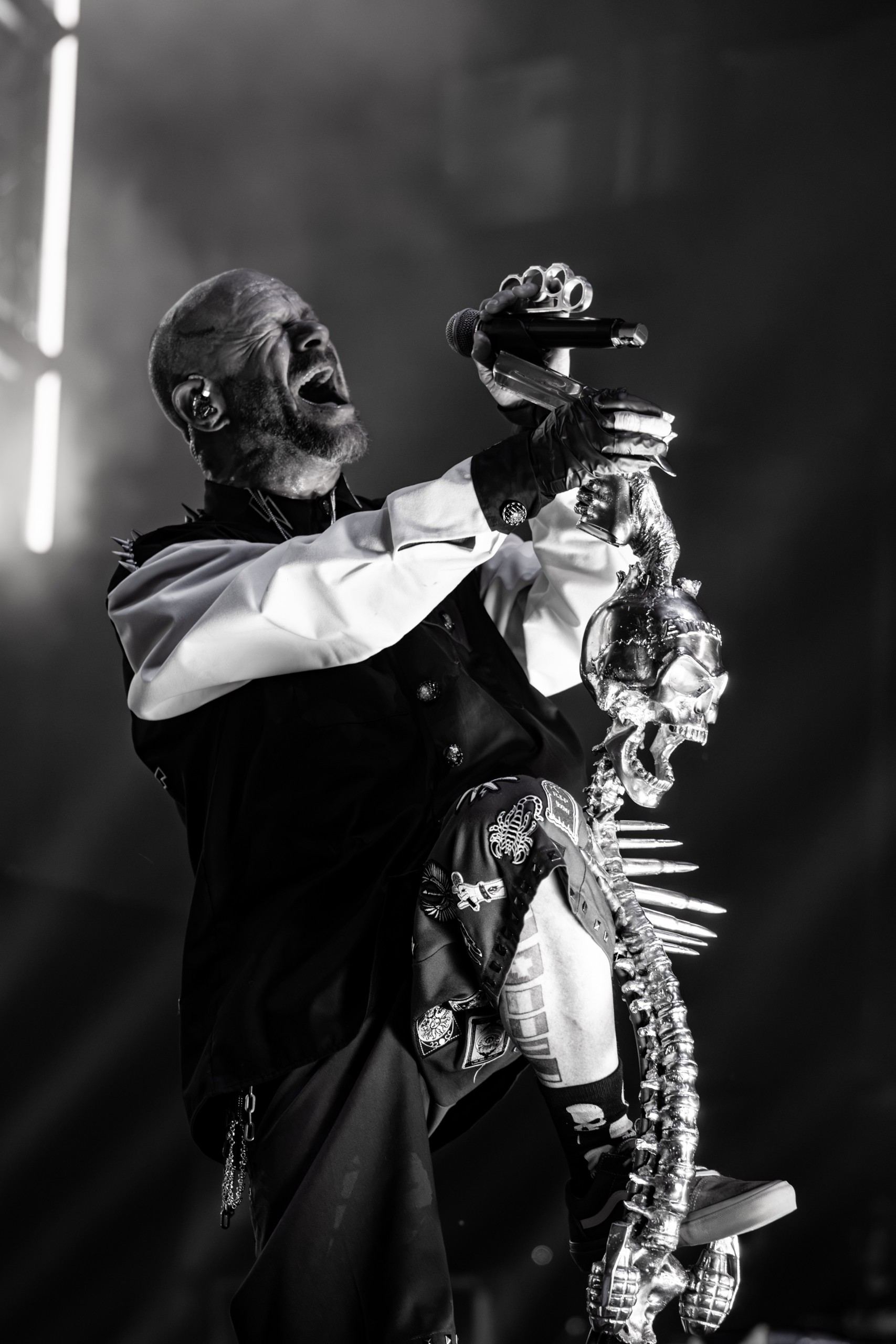 Black-and-white portrait of Ivan Moody at the skeletal microphone stand. Five Finger Death Punch at Coastal Credit Union Music Park, Raleigh, October 14, 2026.