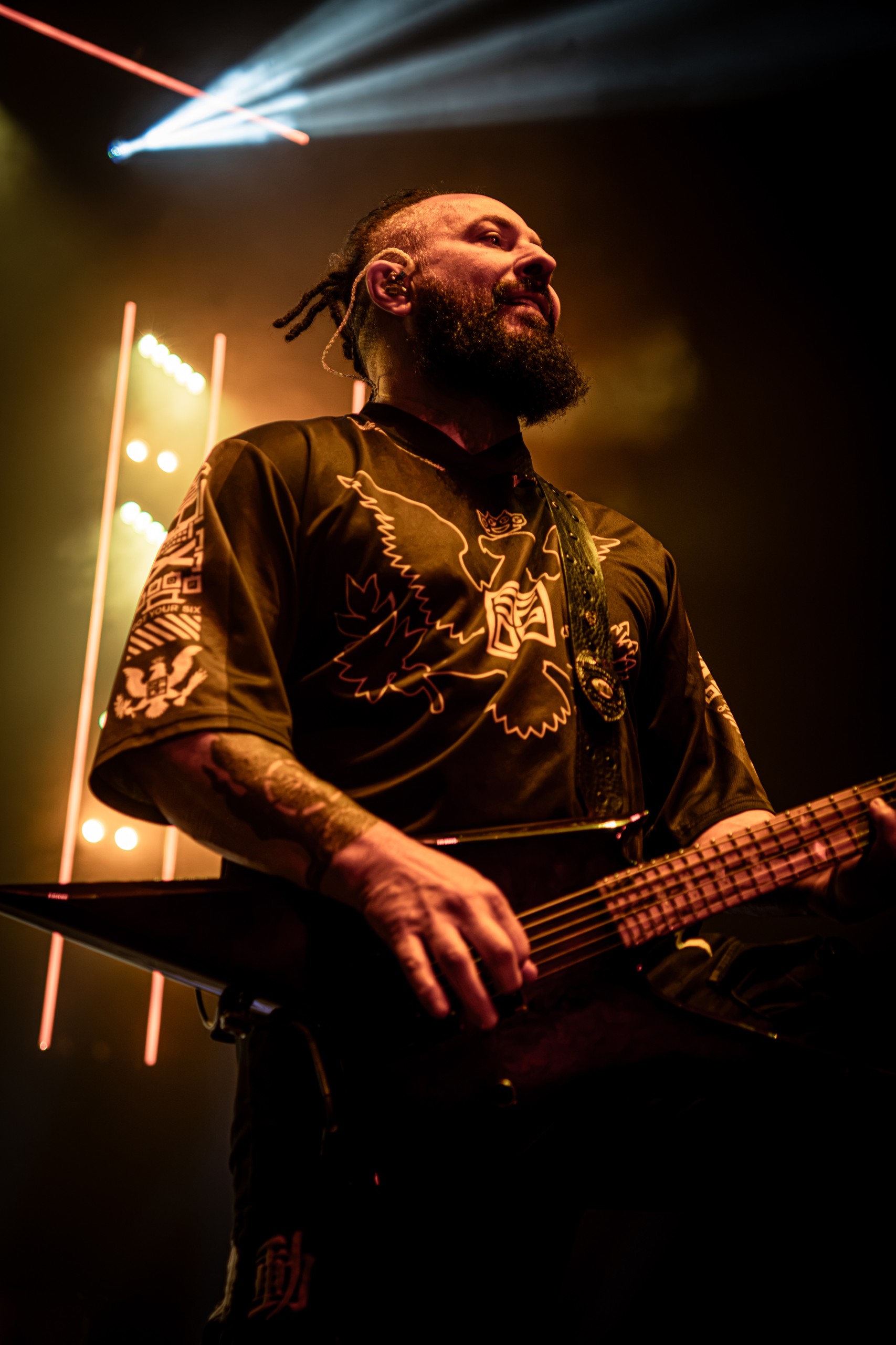 Five Finger Death Punch bassist performing beneath warm stage lights. Five Finger Death Punch at Coastal Credit Union Music Park, Raleigh, October 14, 2026.