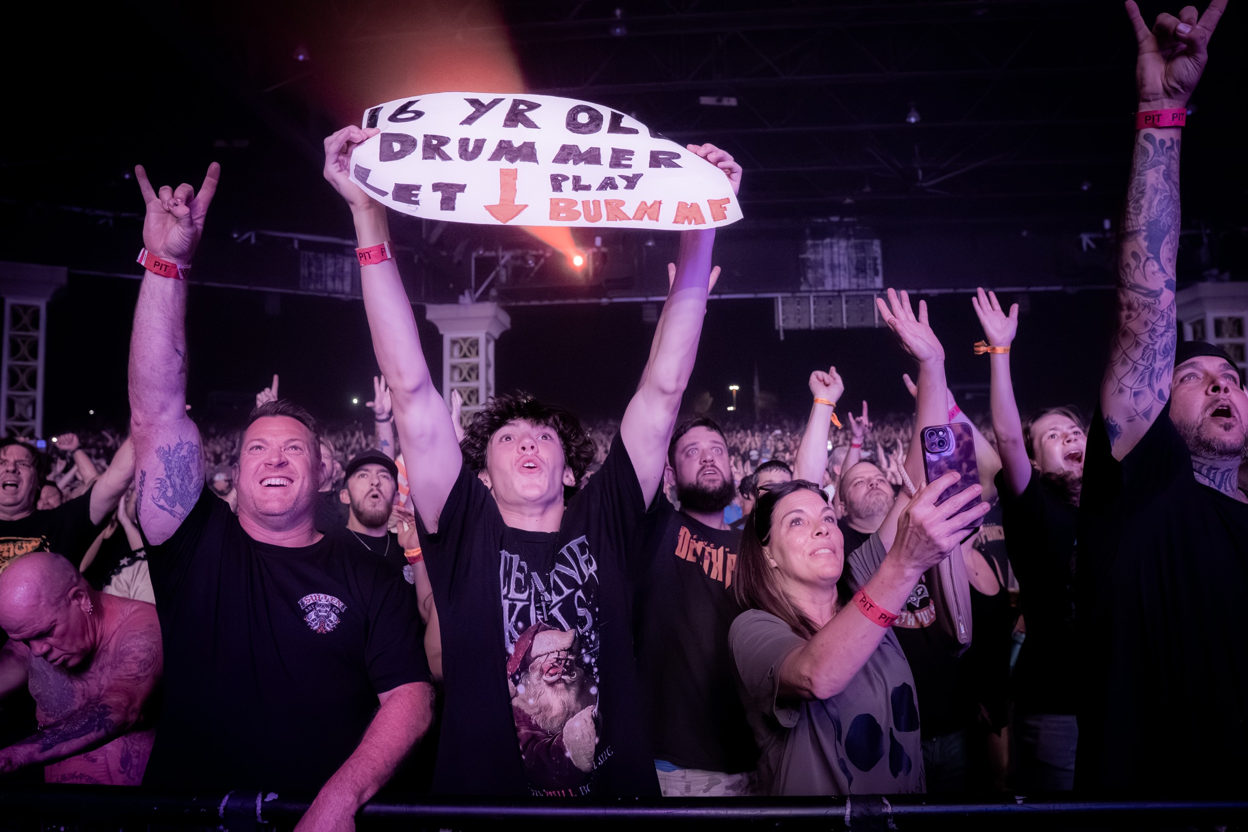 Fans raising their hands and a handmade sign at the barricade. Five Finger Death Punch at Coastal Credit Union Music Park, Raleigh, October 14, 2026.