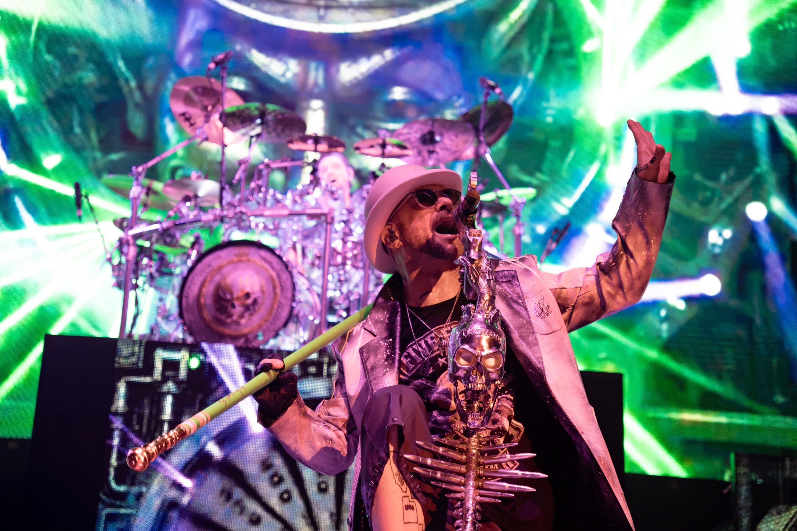 Ivan Moody raising an arm beneath green lights in front of the drum kit. Five Finger Death Punch at Coastal Credit Union Music Park, Raleigh, October 14, 2026.