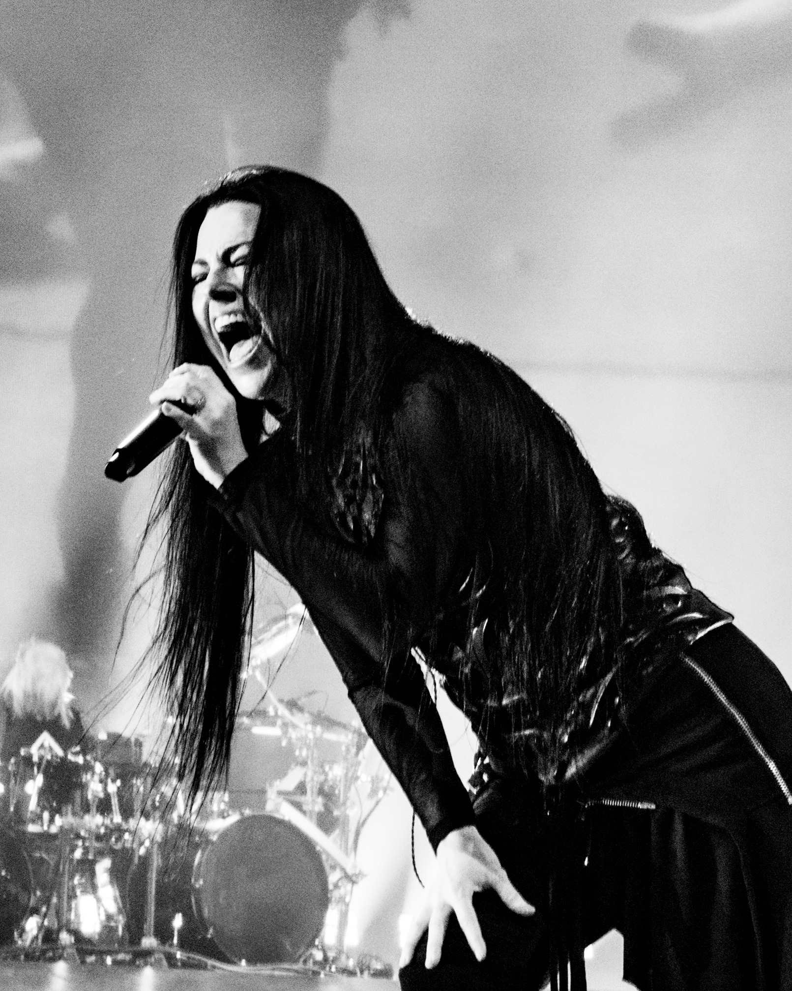 Black and white portrait of Amy Lee leaning toward the microphone.