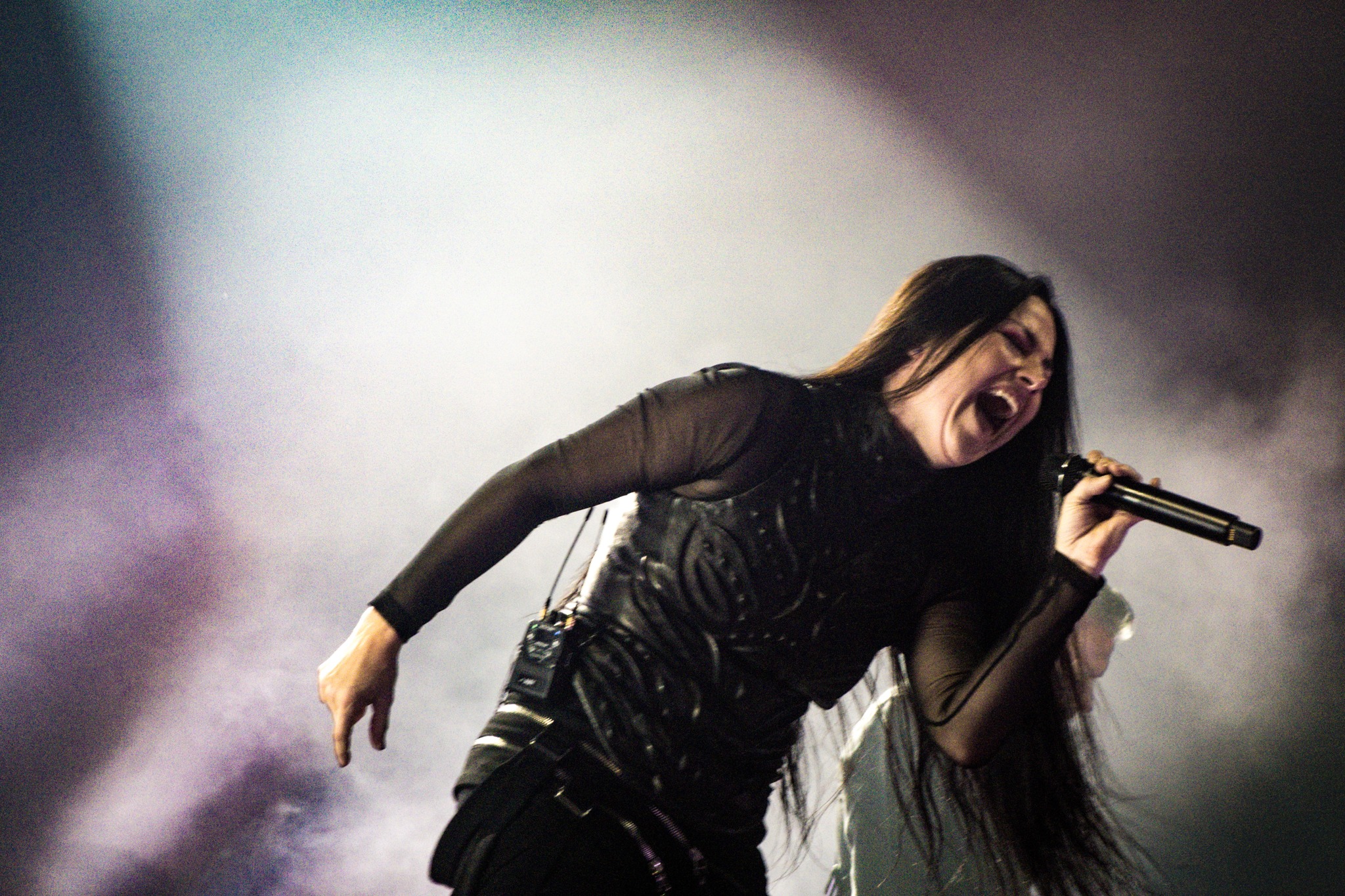 Amy Lee leaning forward to sing through stage haze.