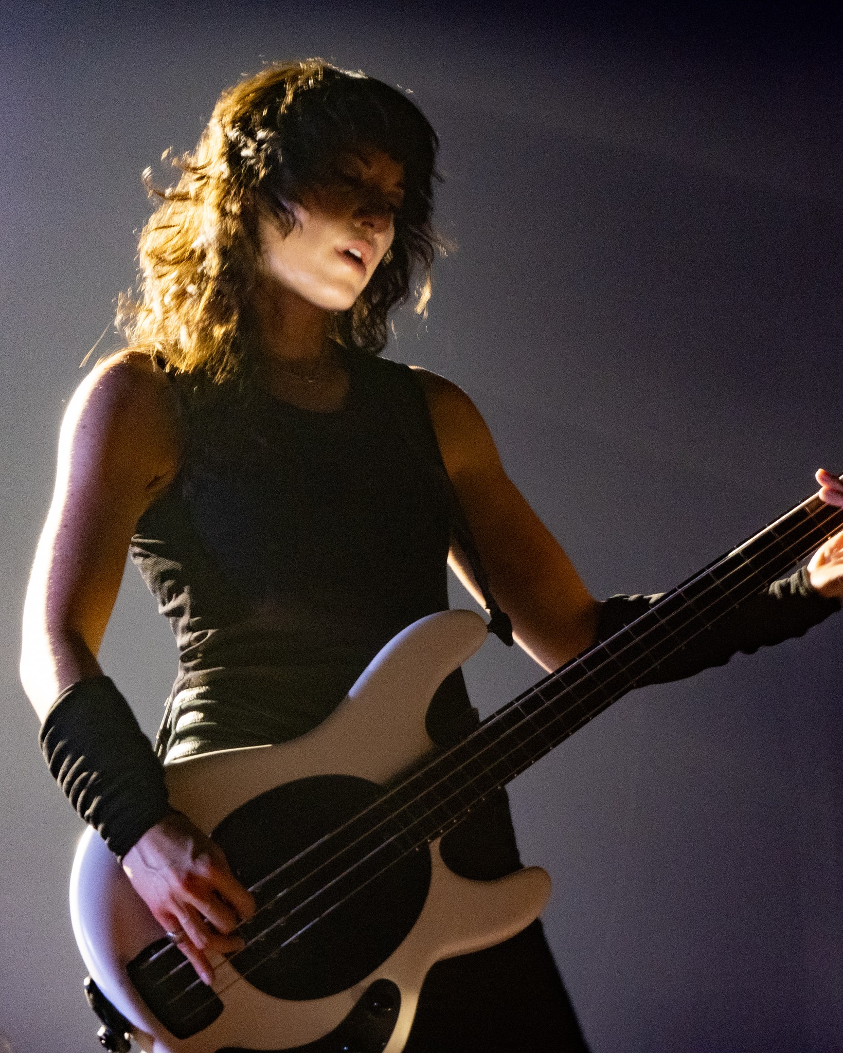 Evanescence bassist performing beneath warm stage light.