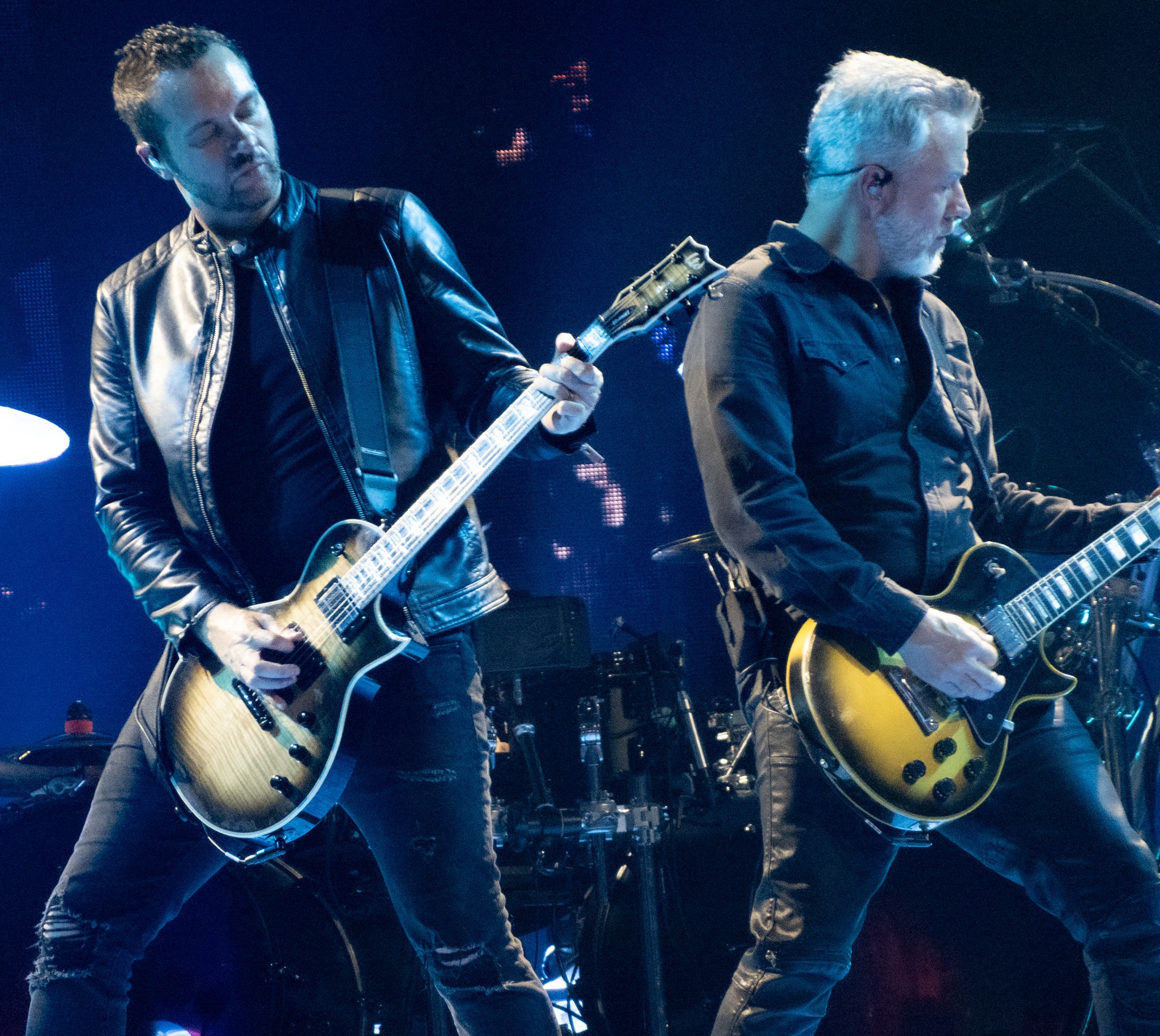 Two Evanescence guitarists playing together under blue light.