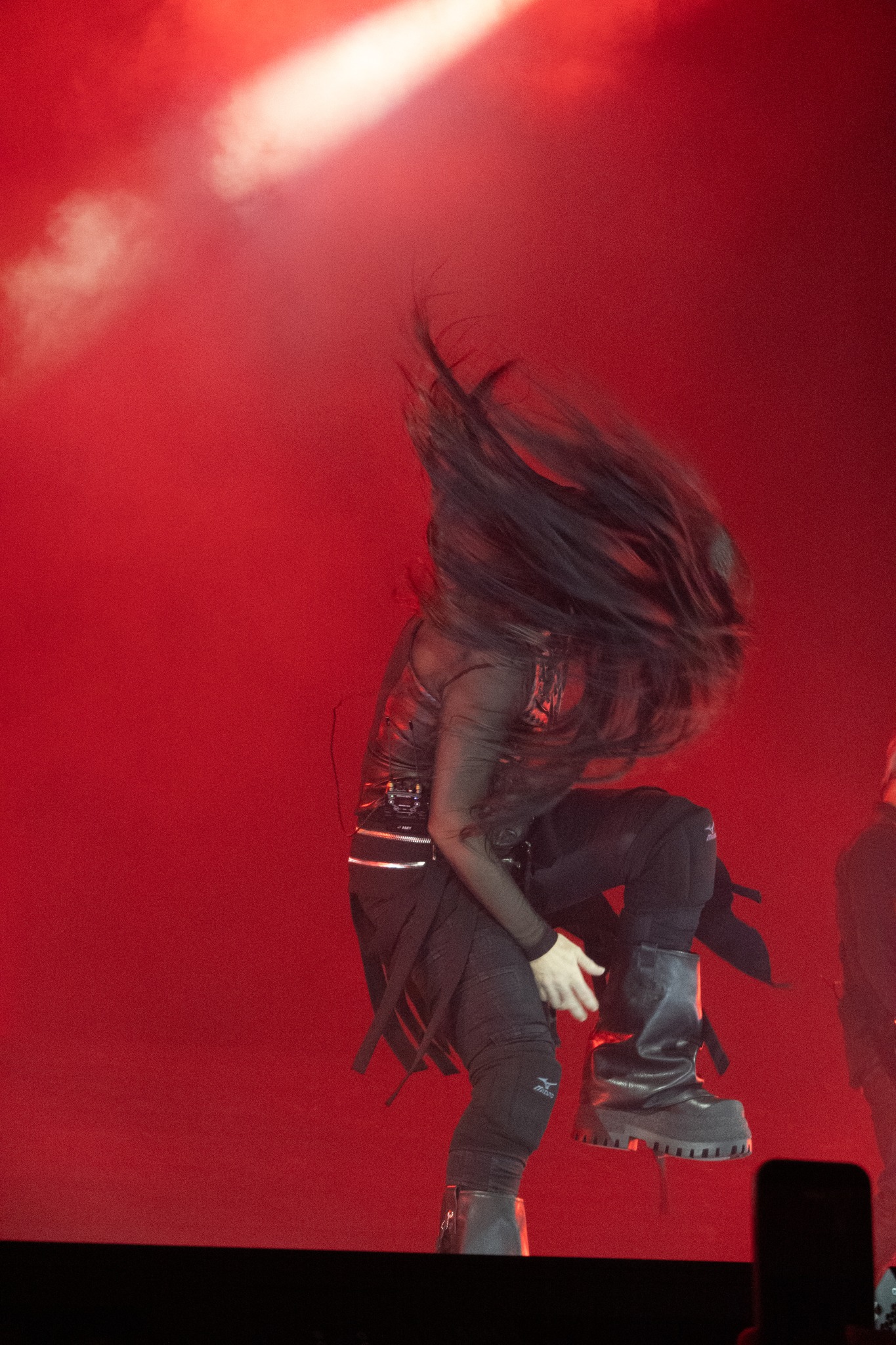 Amy Lee bending forward with her hair swinging under red light.