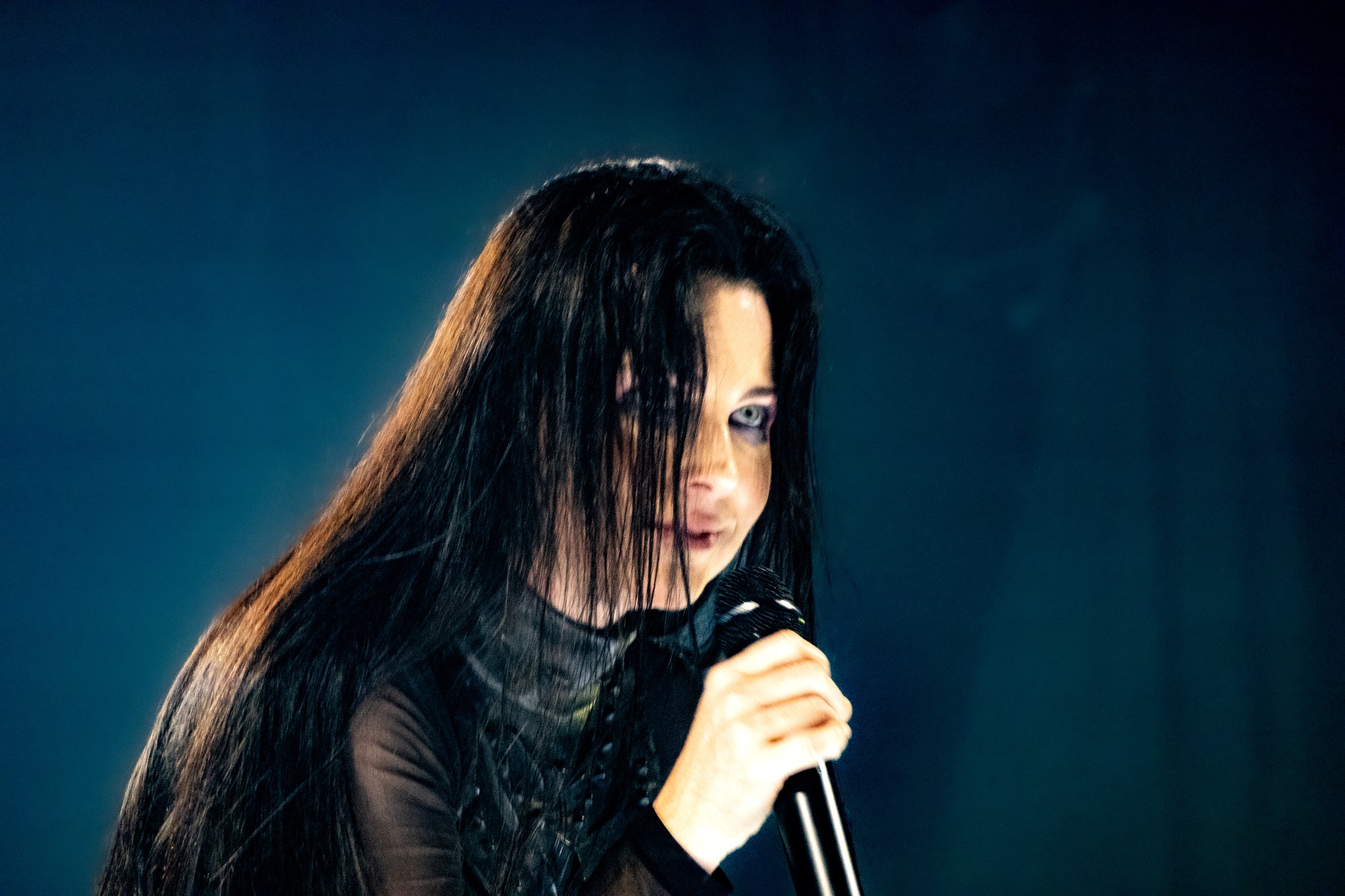 Close view of Amy Lee holding the microphone under blue light.