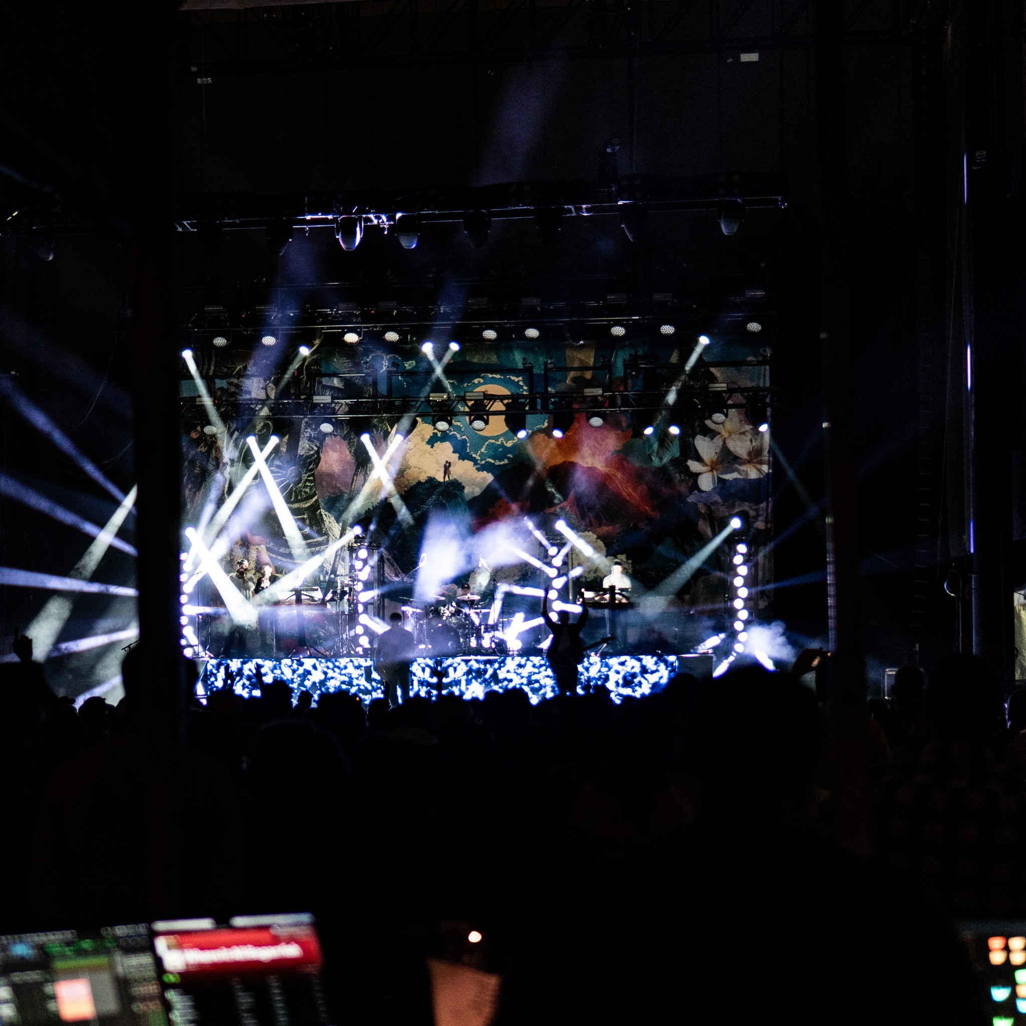 Iration performing beneath beams of white and purple light.