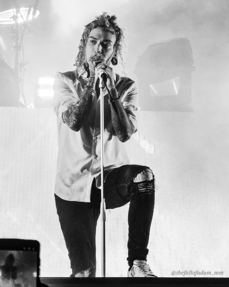 Black and white photograph of Lorna Shore vocalist singing with one foot raised.