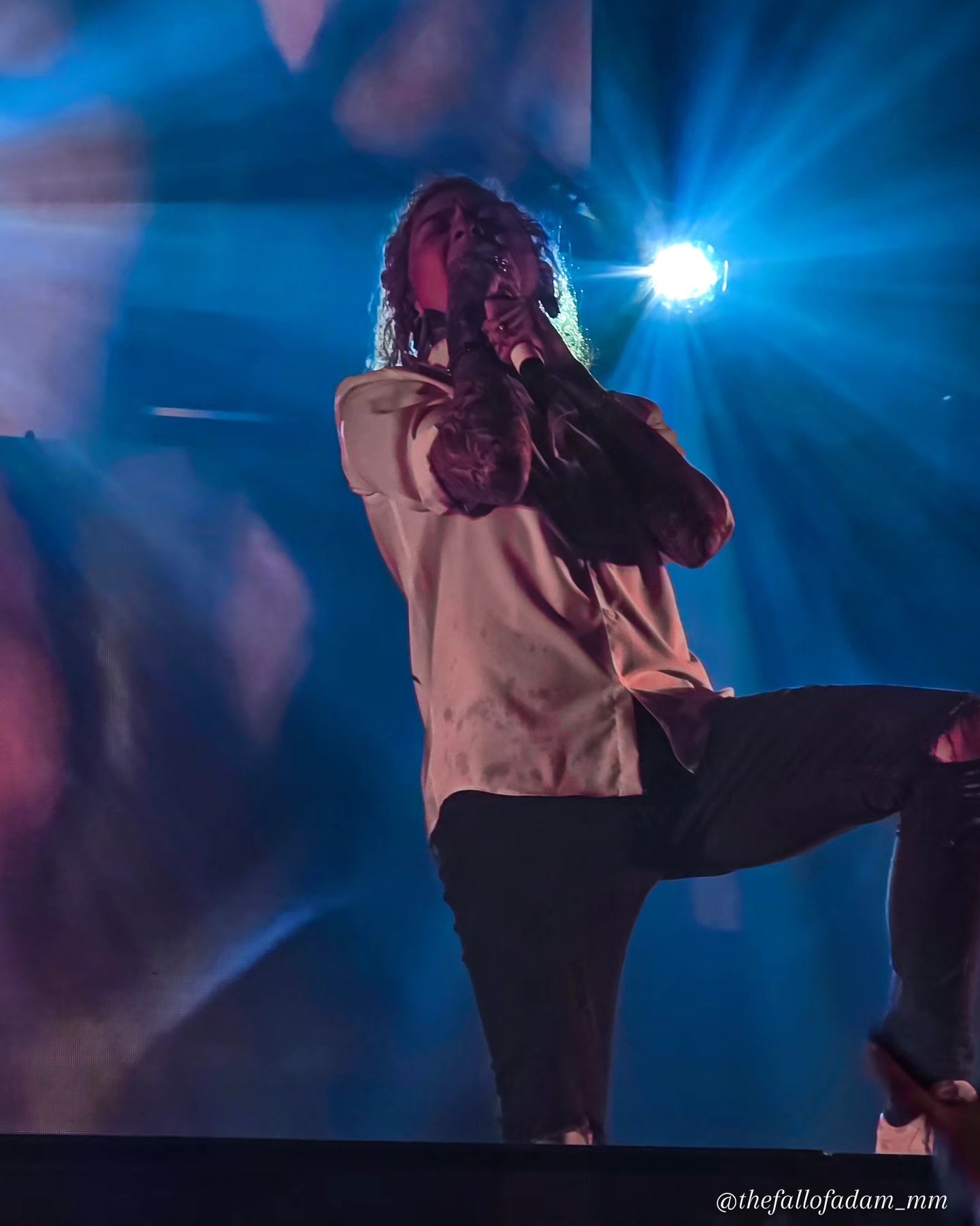 Lorna Shore vocalist singing beneath blue light.