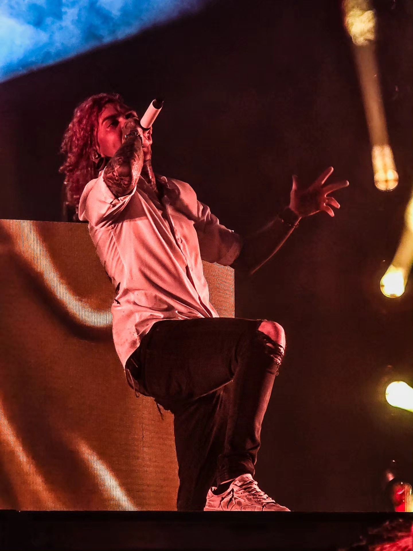 Lorna Shore vocalist gesturing toward the crowd under warm light.