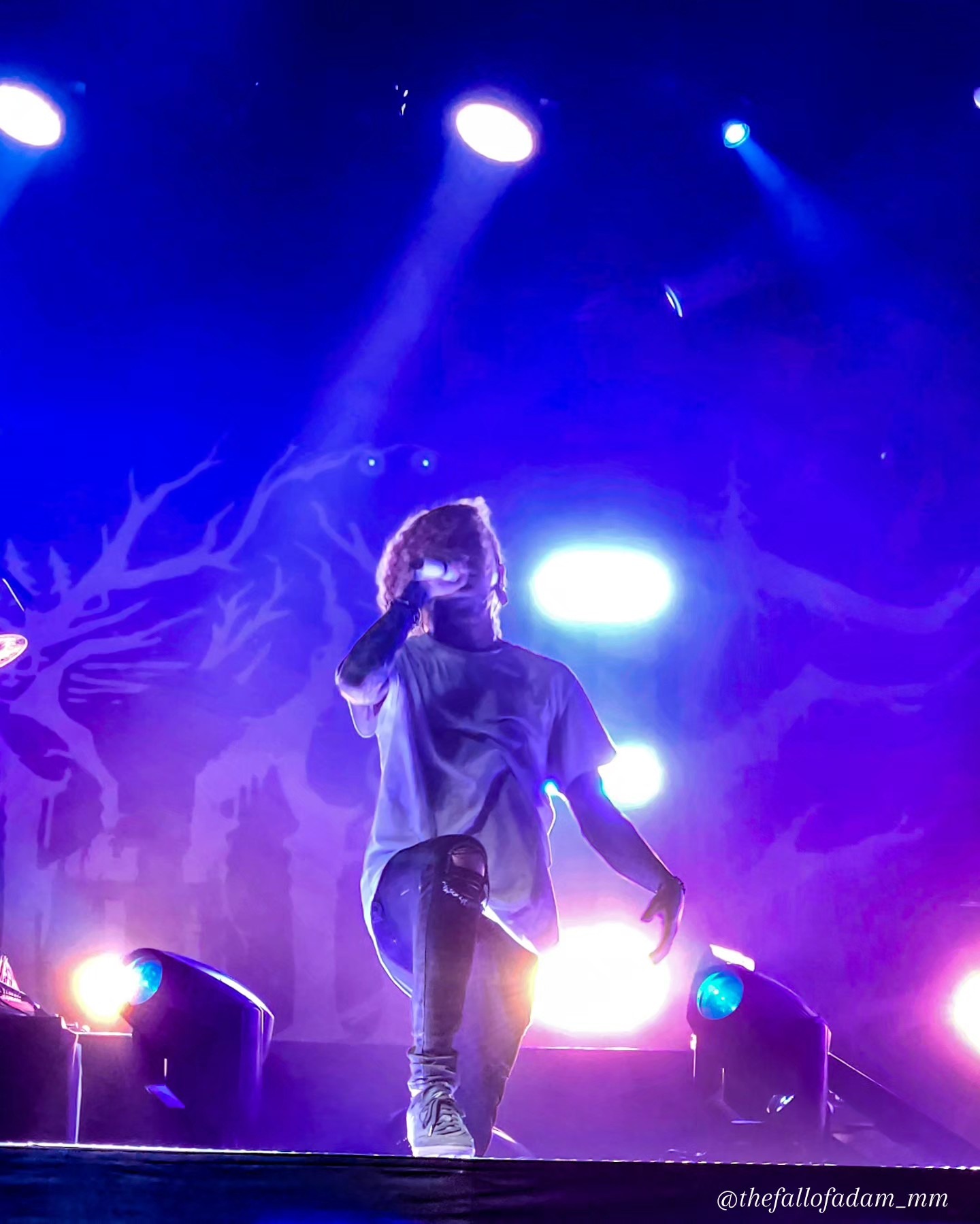 Lorna Shore vocalist performing under blue and pink light.