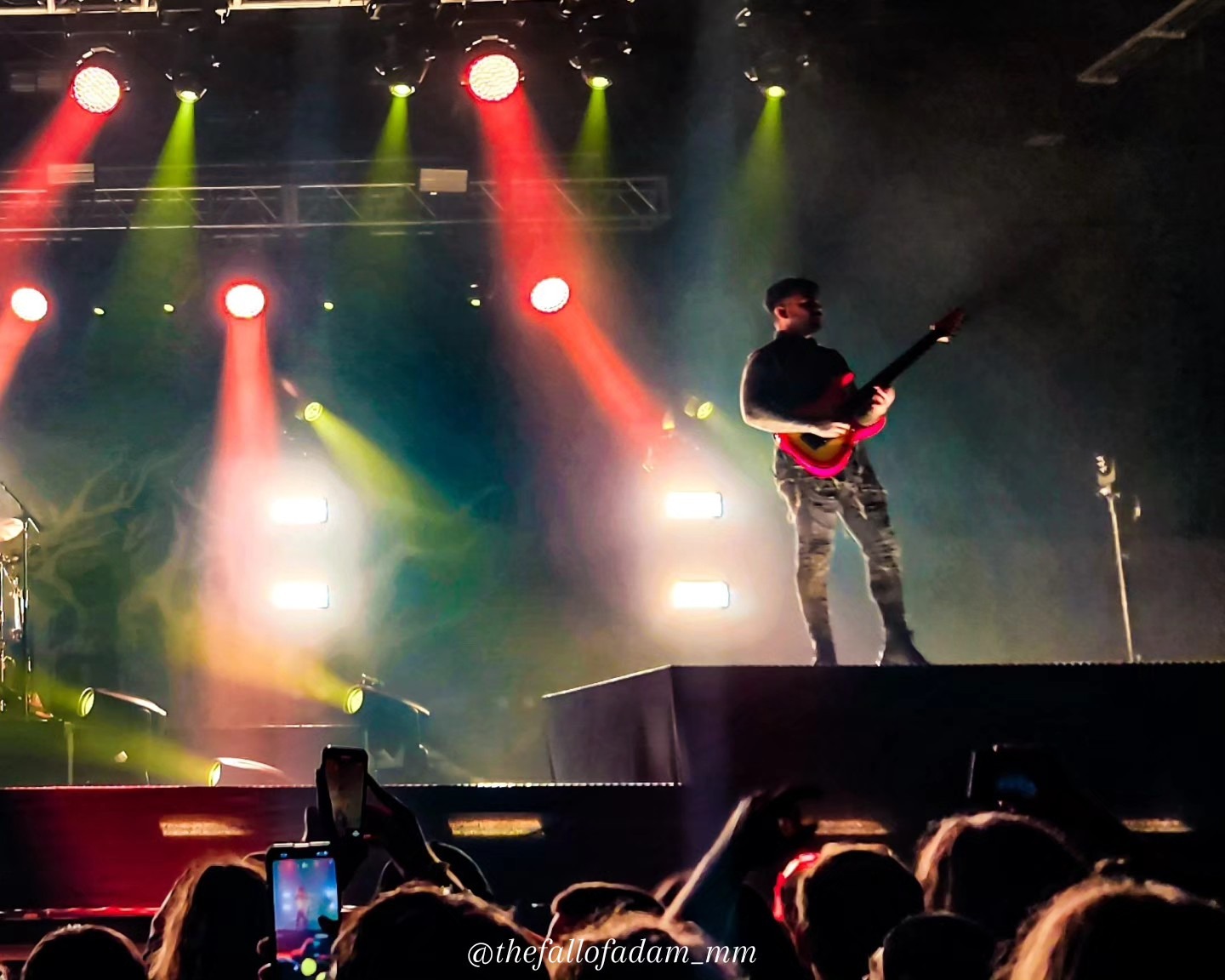 Lorna Shore guitarist performing under multicolored stage lights.