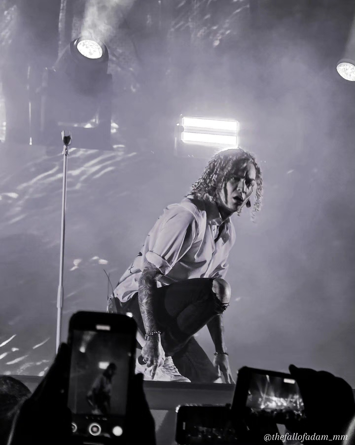 Black and white photograph of Lorna Shore vocalist crouching at the stage edge.