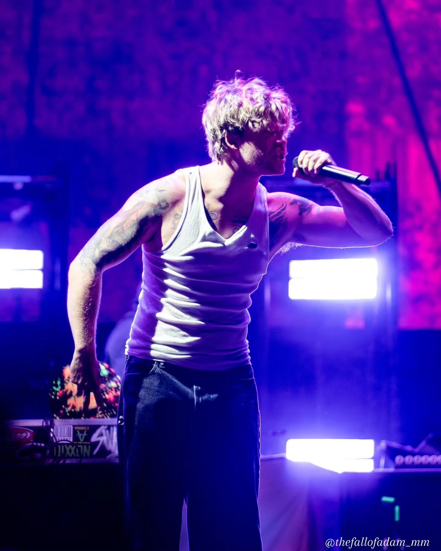 Sublime vocalist leaning forward under purple light.