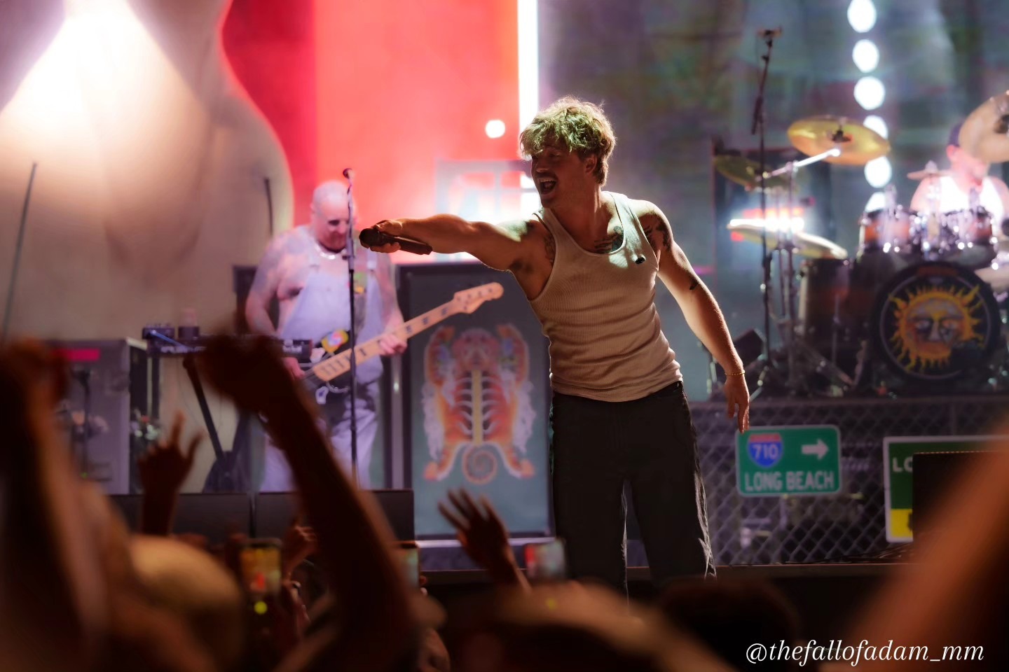 Sublime vocalist reaching toward the audience under red light.