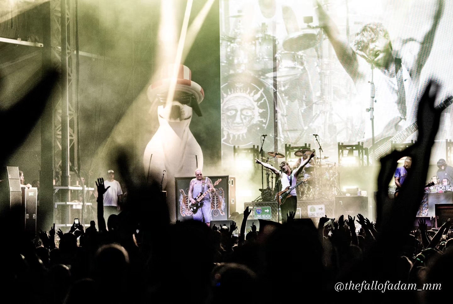 Fans raising their hands toward Sublime under bright stage lights.