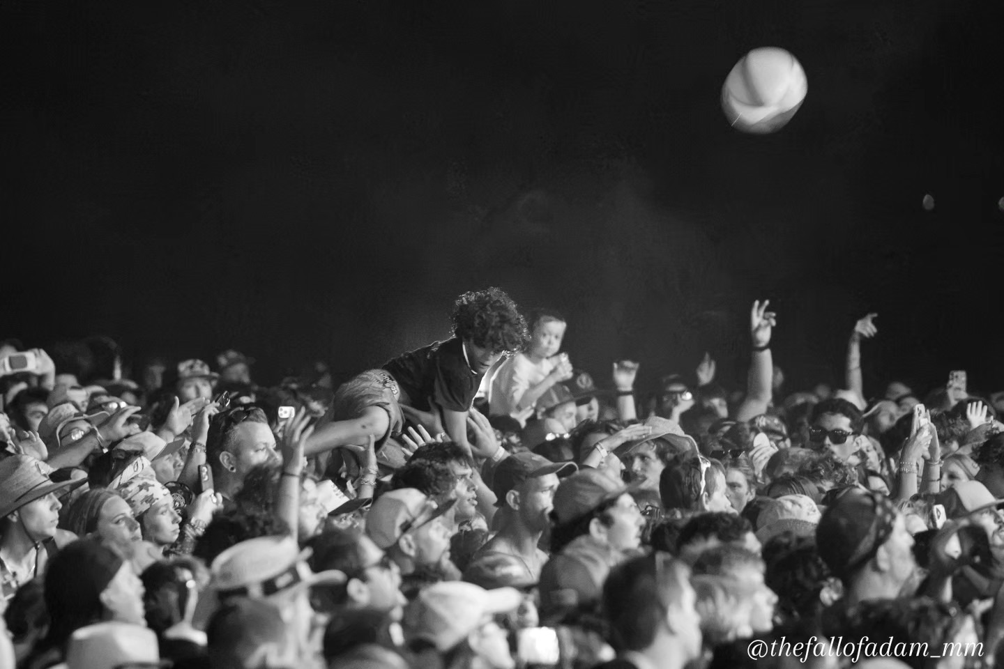 Black and white photograph of a beach ball above the festival crowd.
