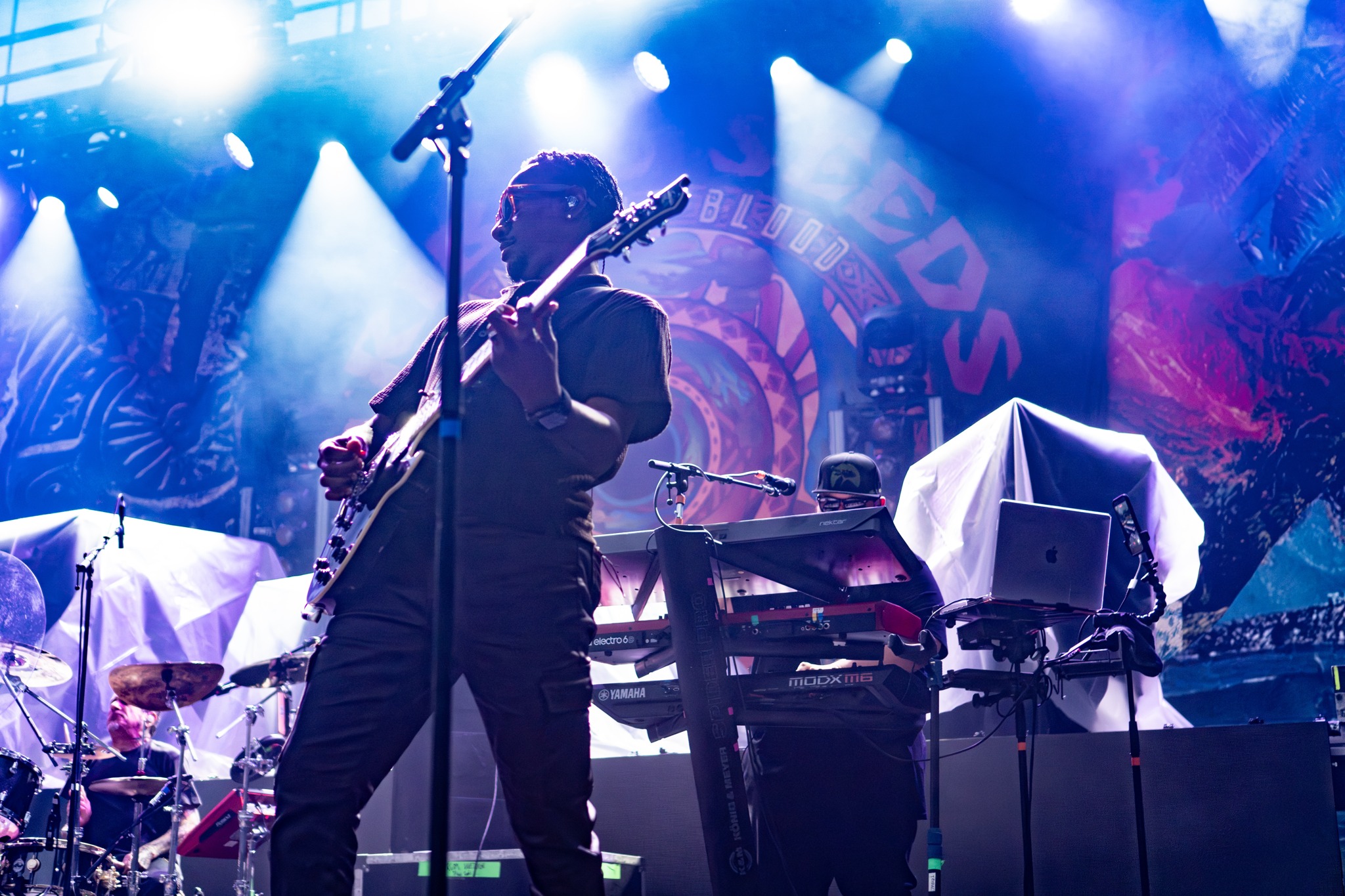 Tribal Seeds guitarist performing beneath blue and white light.