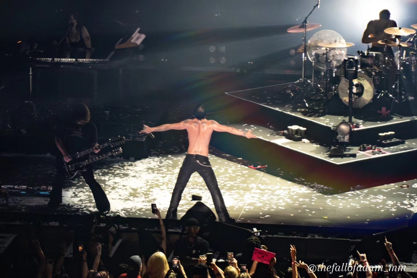 Yungblud spreading his arms toward the audience on a confetti-covered stage.