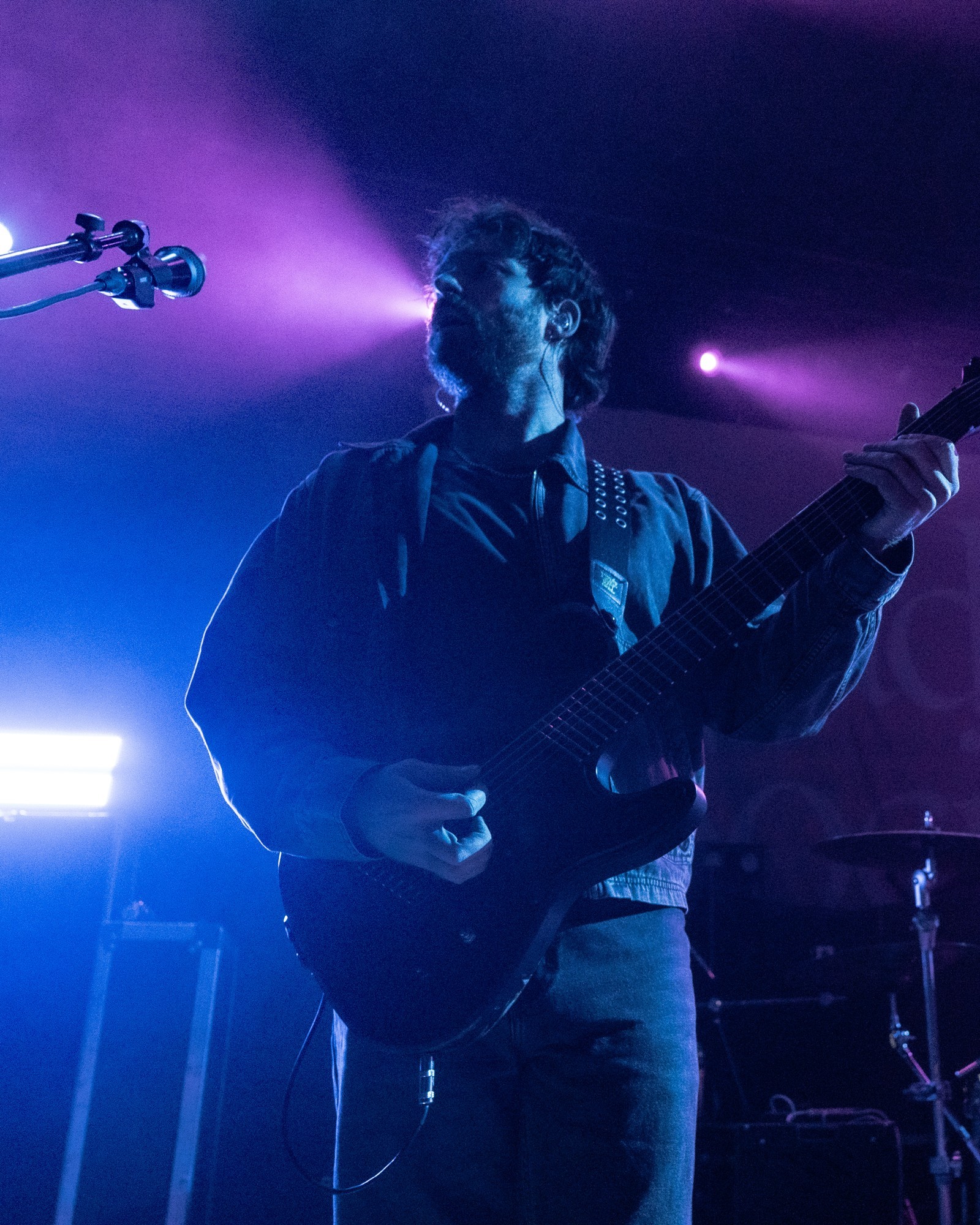 Dead Poet Society guitarist performing beneath blue lights.