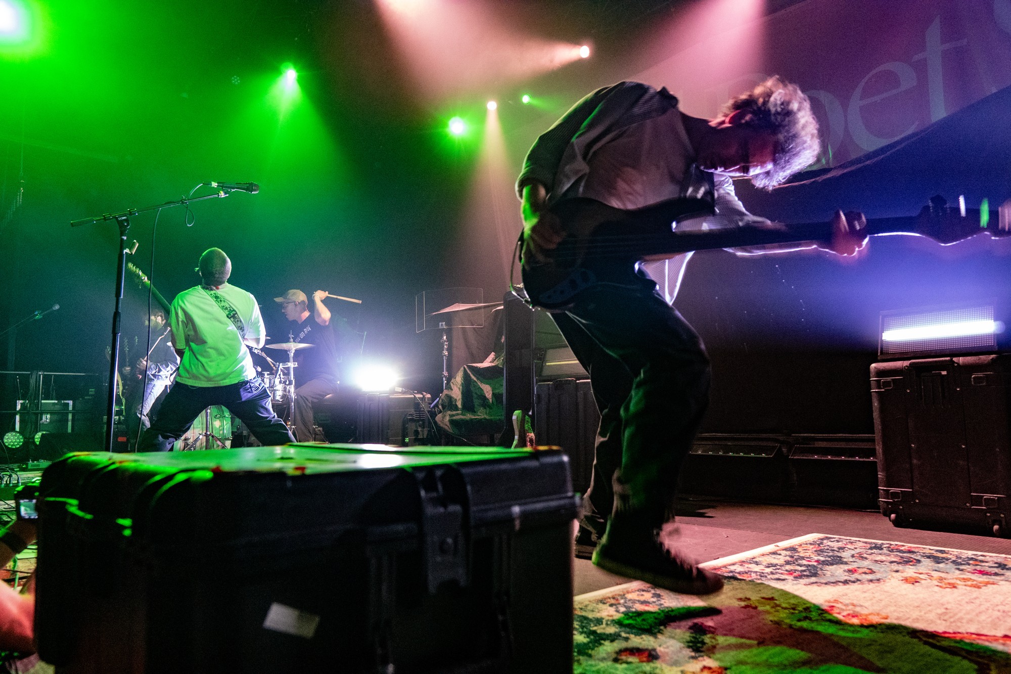 Dead Poet Society guitarist bending toward the crowd beneath green lights.