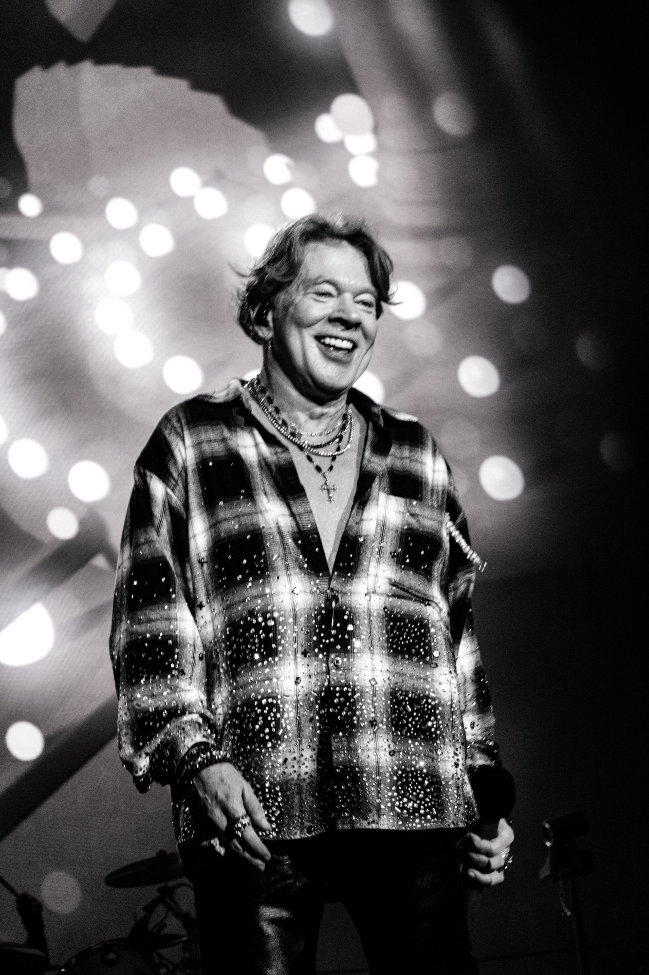 Black and white photograph of Axl Rose smiling onstage.
