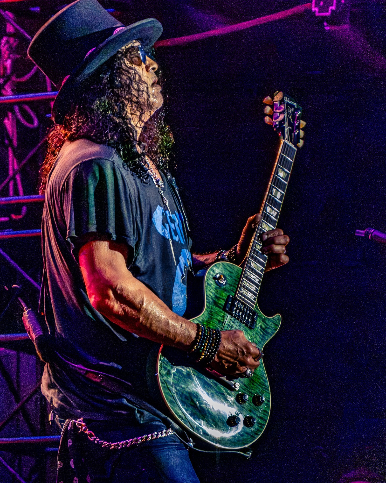 Slash playing a green guitar under purple lighting.