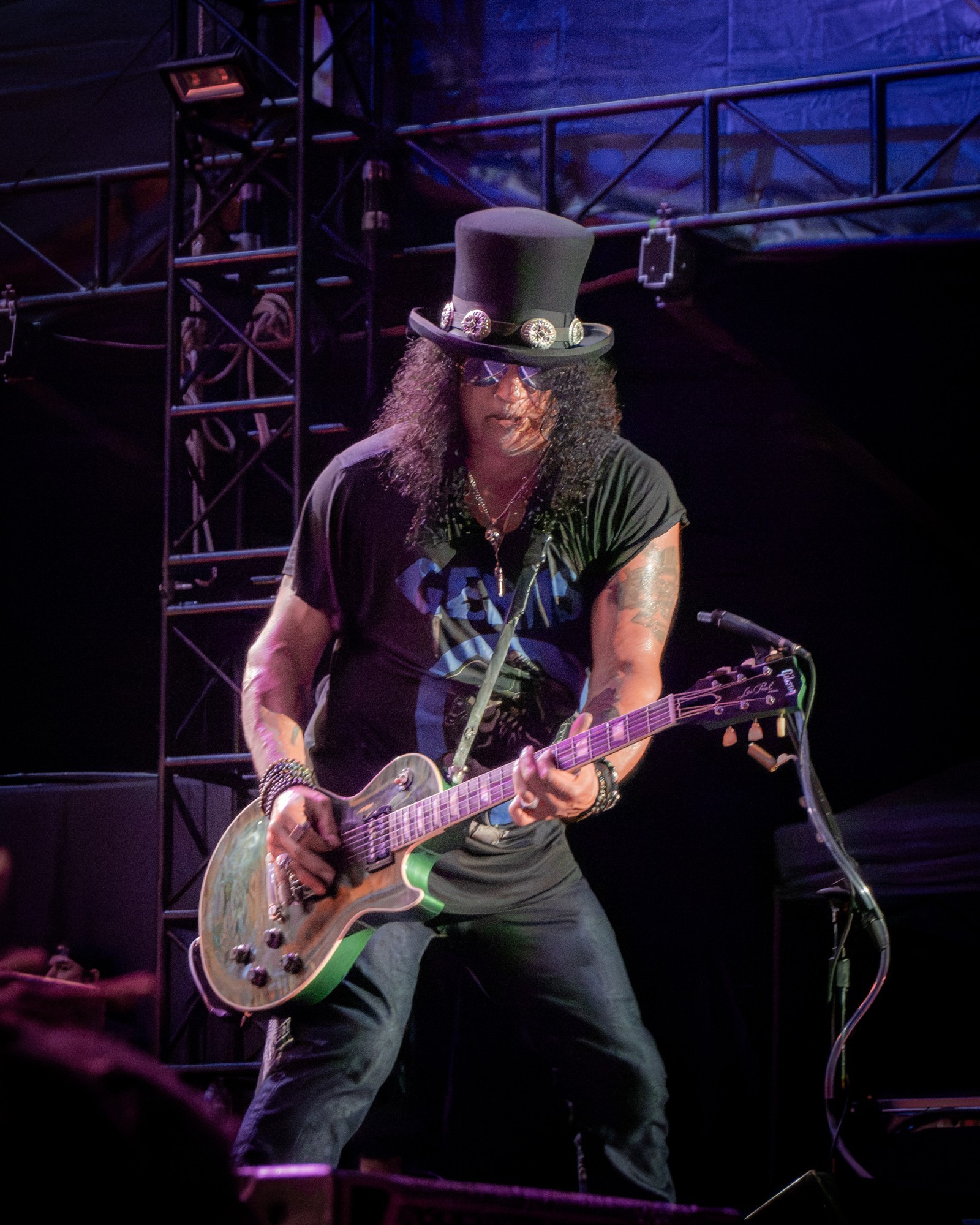 Slash leaning into his guitar onstage.