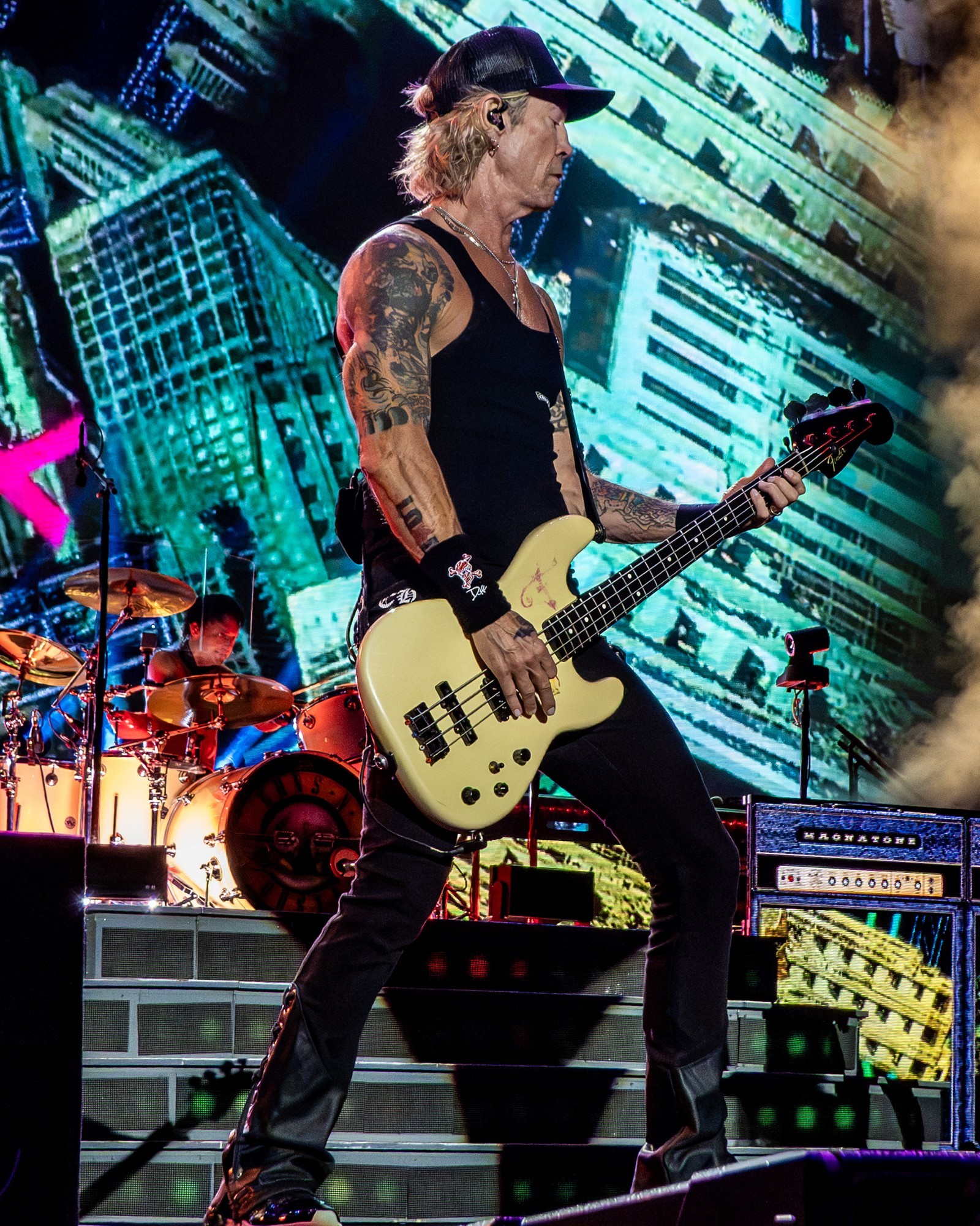 Duff McKagan playing bass in front of the stage screens.