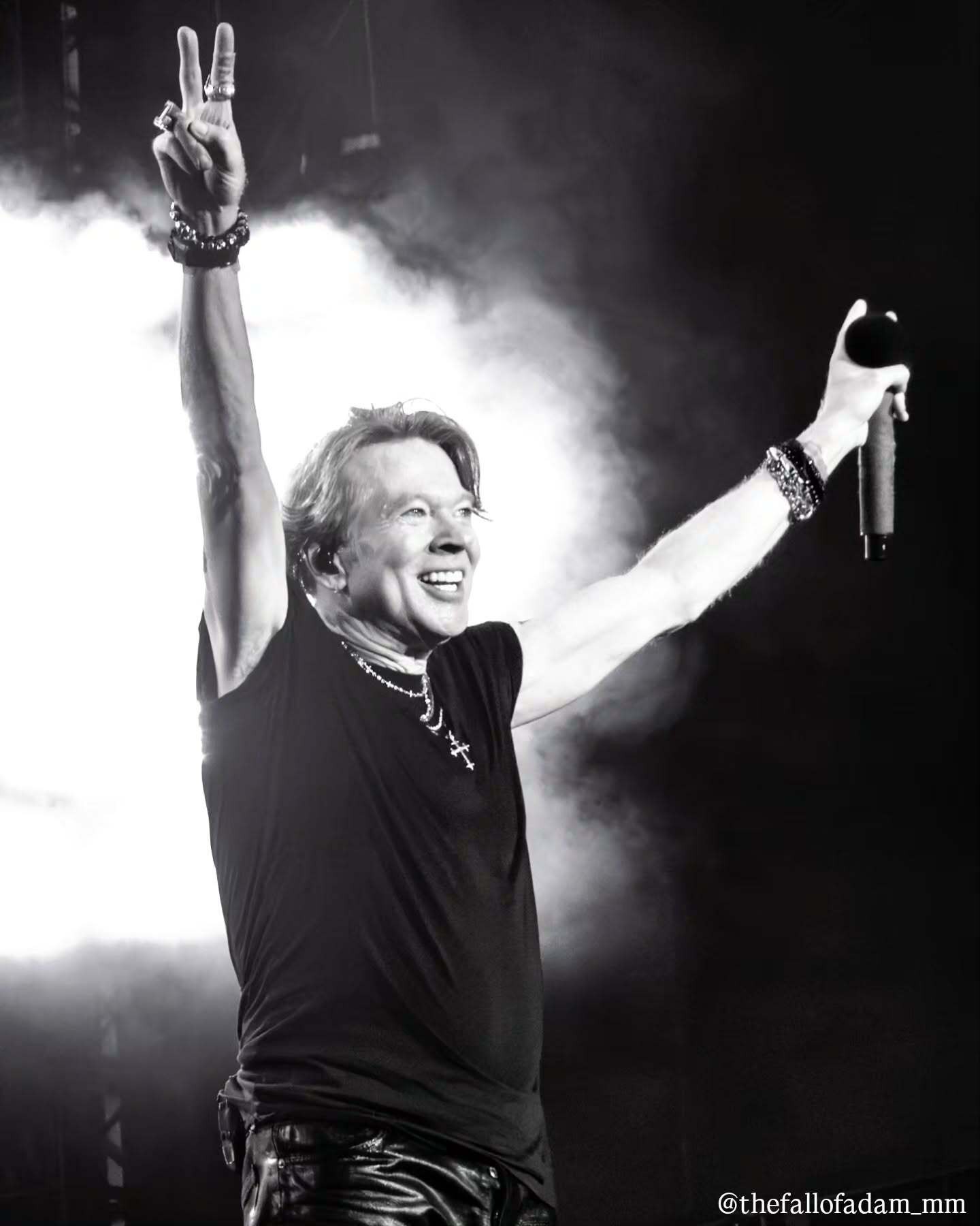 Black and white photograph of Axl Rose raising both arms.