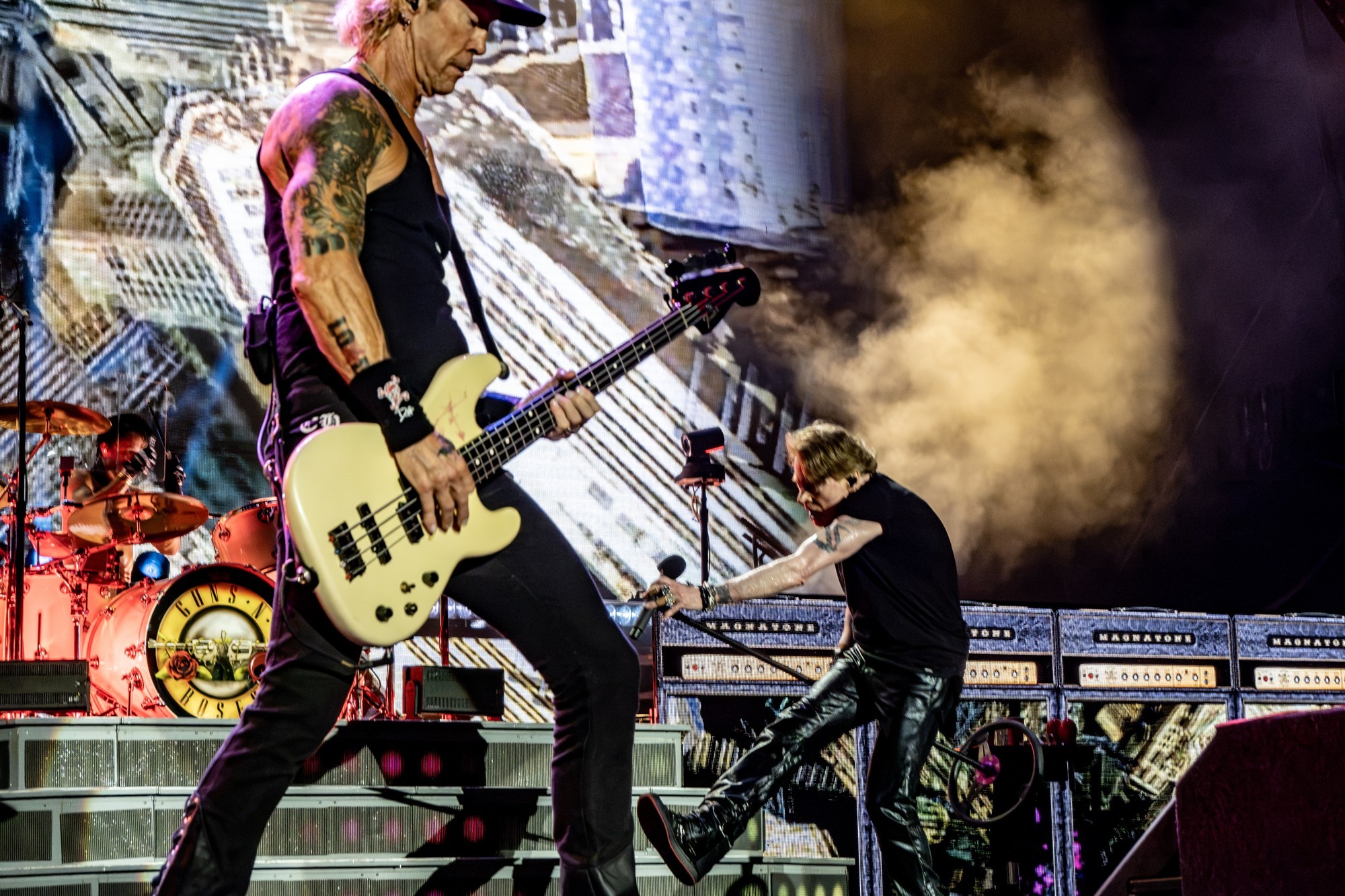 Duff McKagan playing bass near the front of the stage.