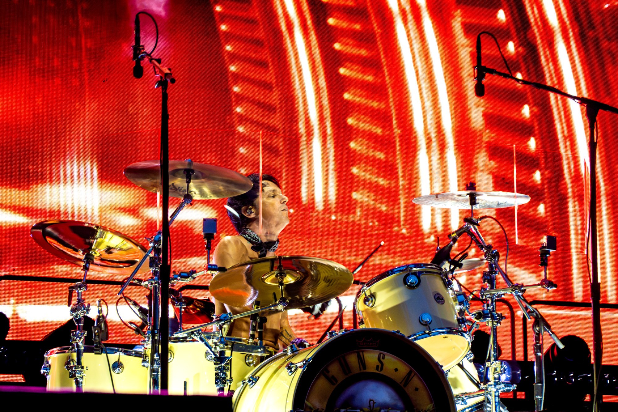 Guns N’ Roses drummer performing before red stage screens.