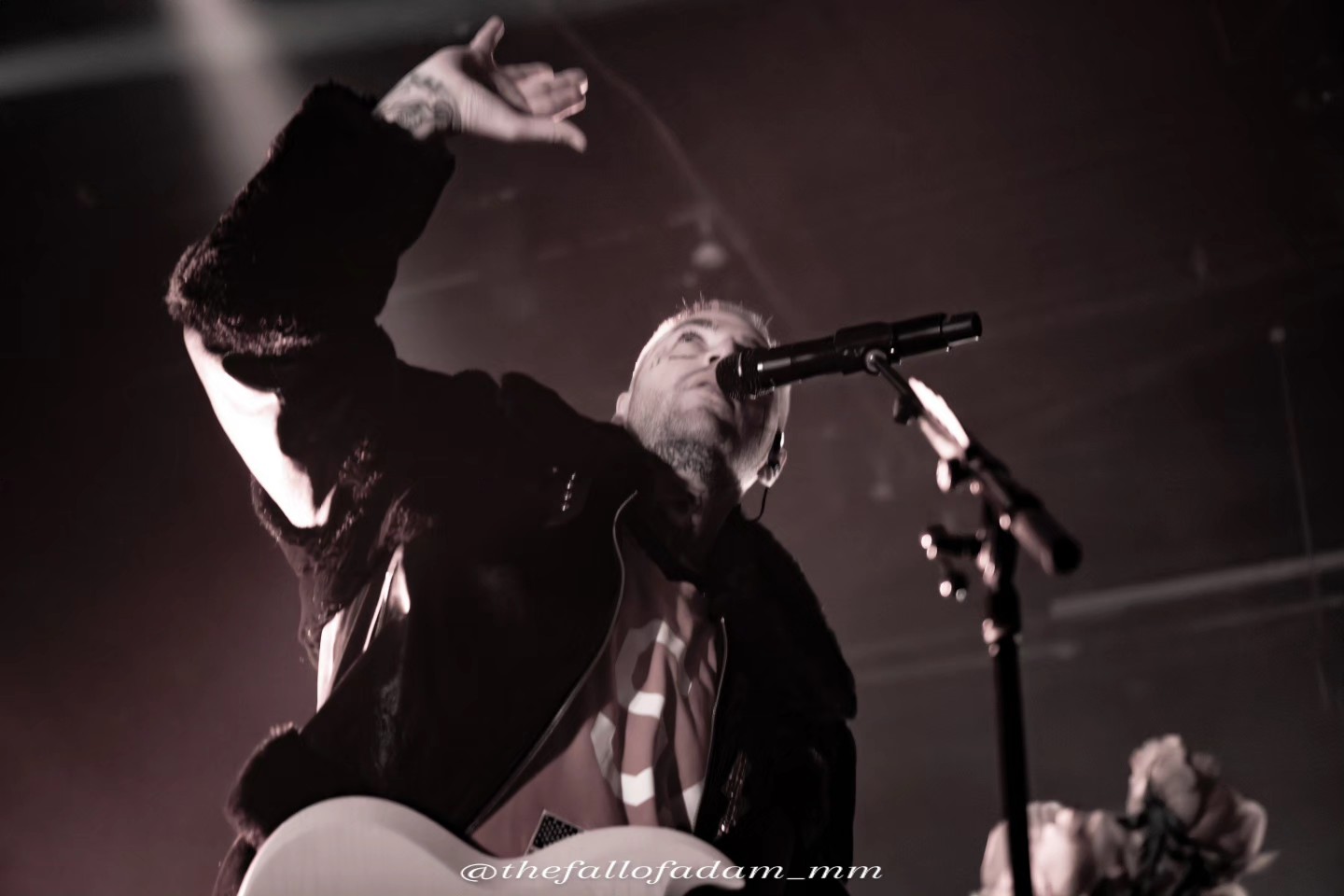 Highly Suspect vocalist raising his hand at the microphone in black and white.