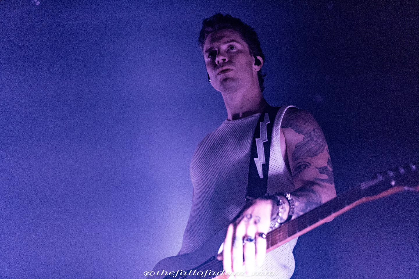 Highly Suspect guitarist looking toward the audience under purple light.