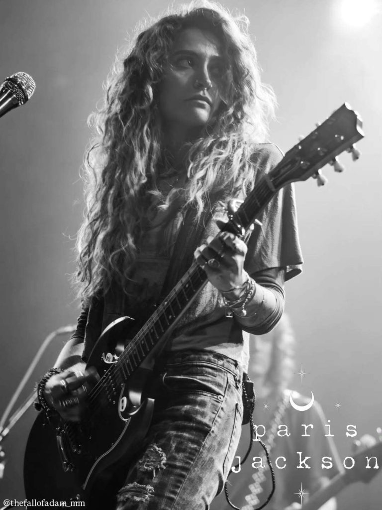 Black and white portrait of Paris Jackson playing guitar.