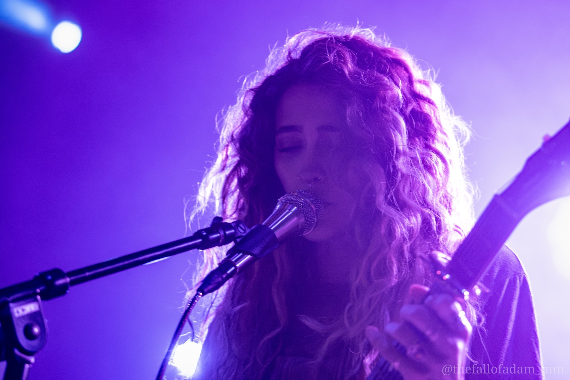 Close portrait of Paris Jackson singing under violet lights.