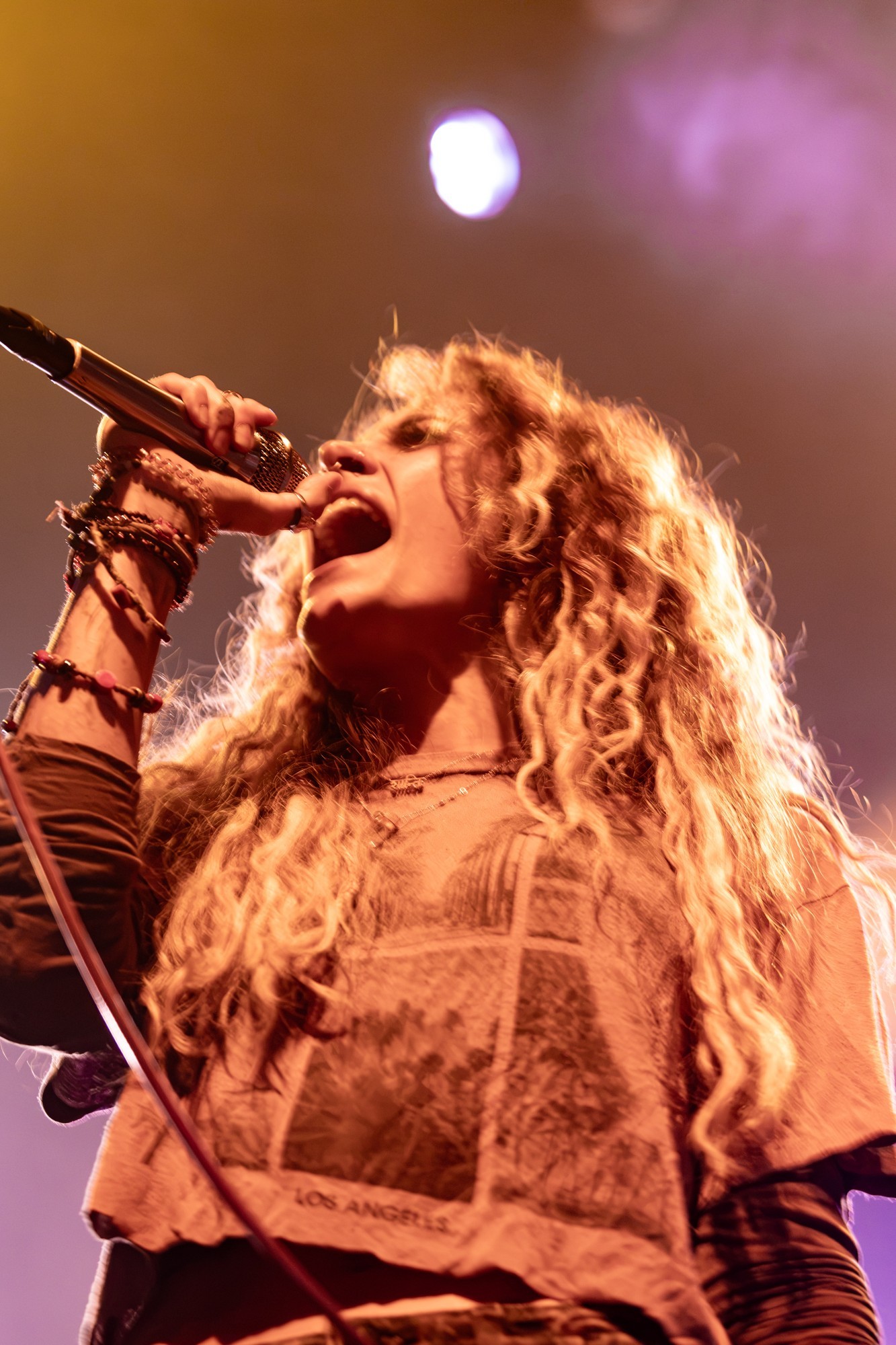 Paris Jackson singing beneath warm amber lighting.