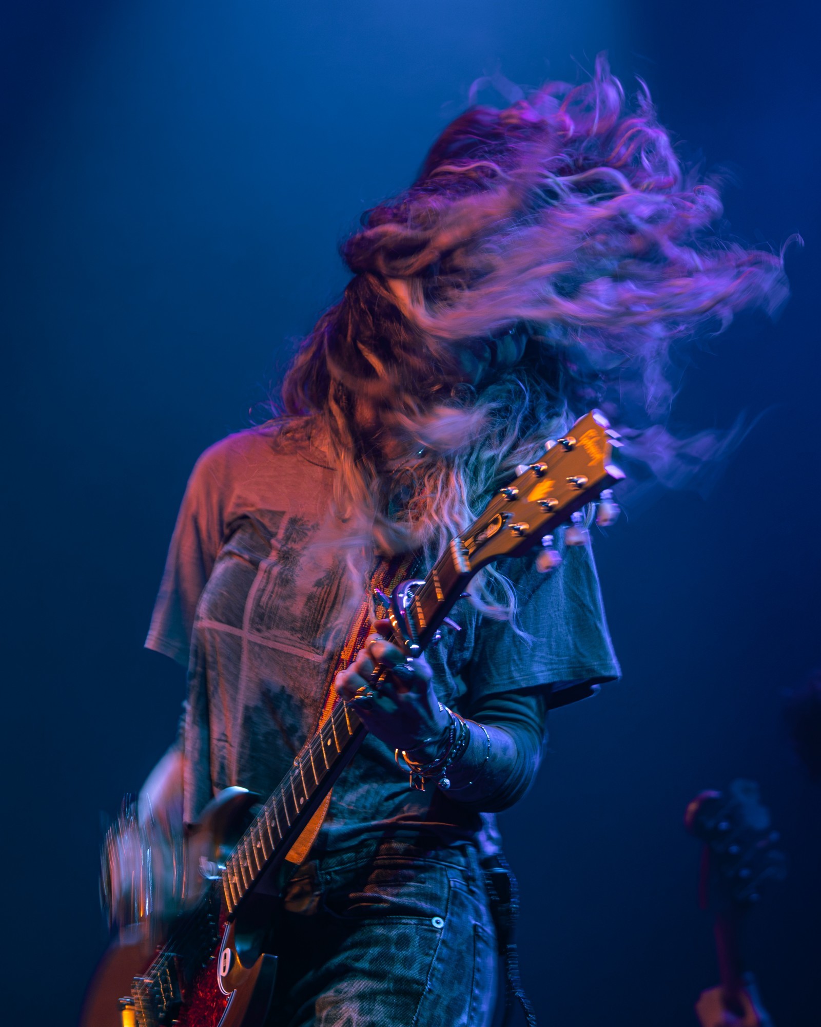 Paris Jackson playing guitar with her hair in motion.