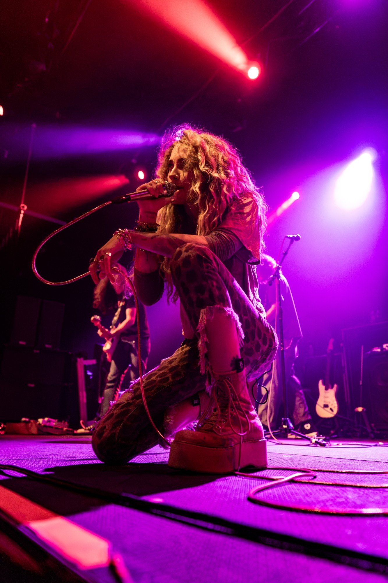 Paris Jackson playing guitar near the front of the stage.