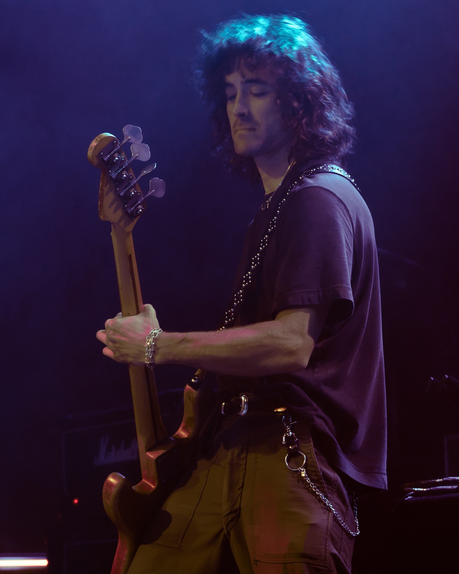 Paris Jackson bassist performing beneath blue lights.