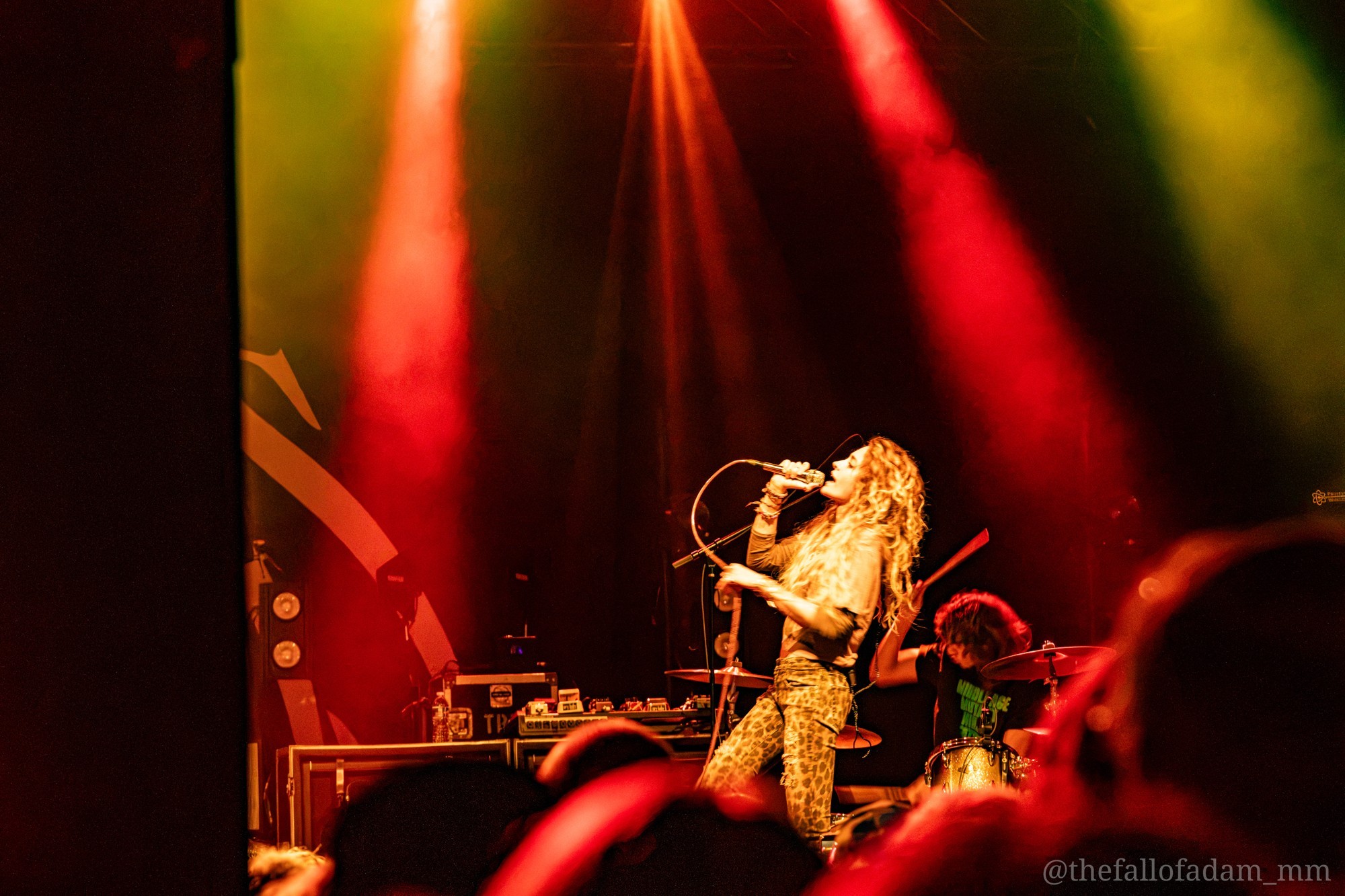 Paris Jackson kneeling near the audience beneath red and gold lights.