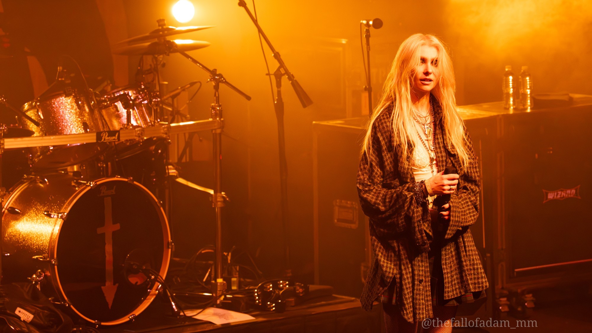 The Pretty Reckless onstage beneath warm amber lights.