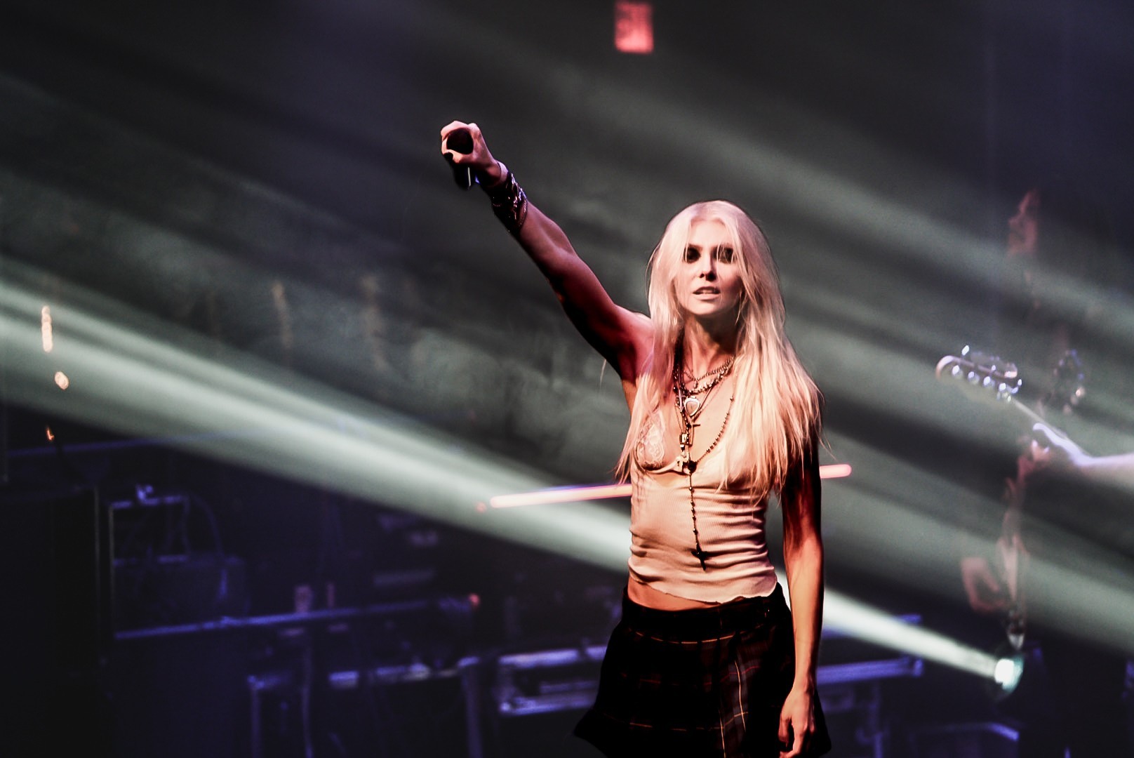 Taylor Momsen raising her arm against white stage beams.
