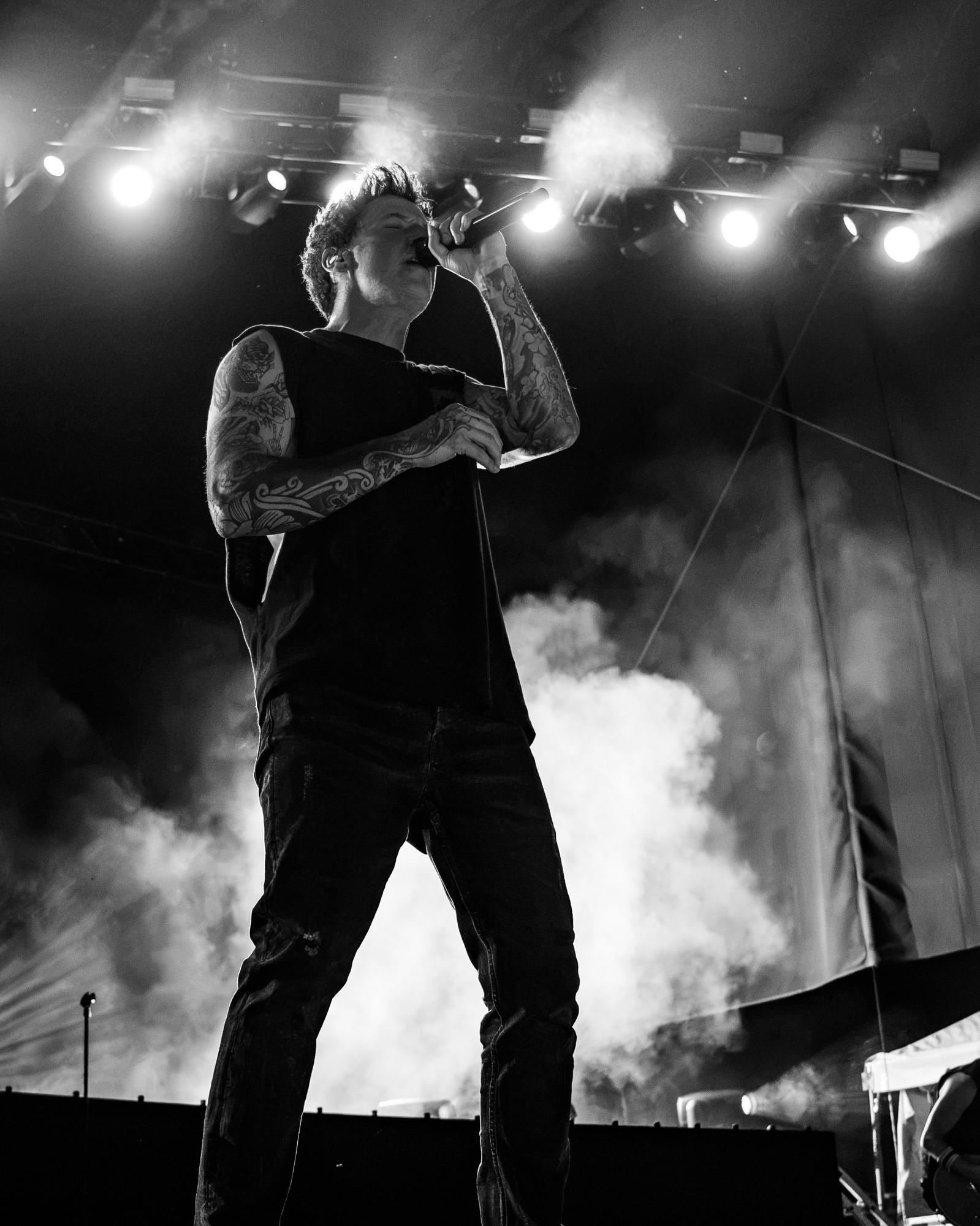 Black and white photograph of the Simple Plan vocalist amid stage smoke.