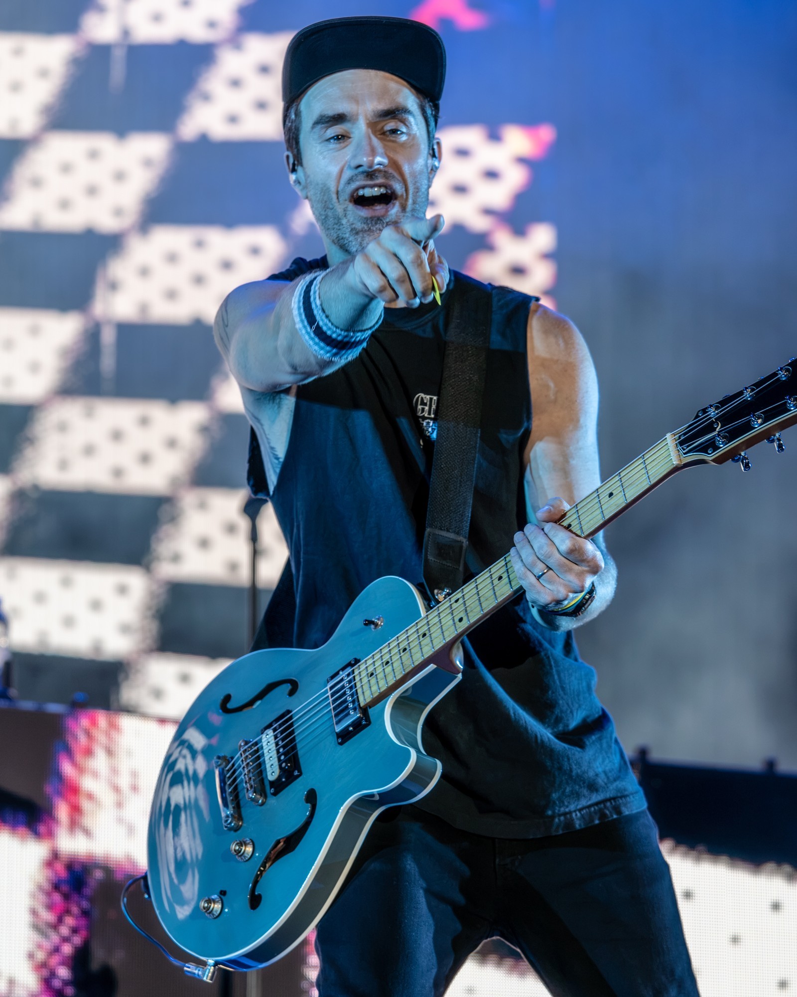 Simple Plan guitarist pointing toward the camera with his guitar.