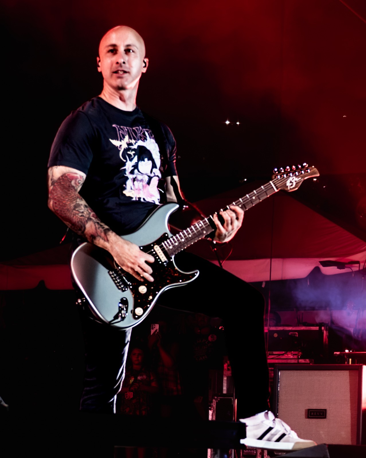 Simple Plan guitarist singing beneath red lighting.