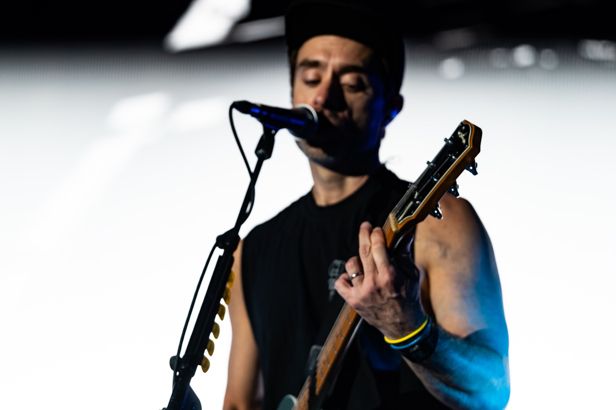 Close portrait of a Simple Plan guitarist singing at the microphone.