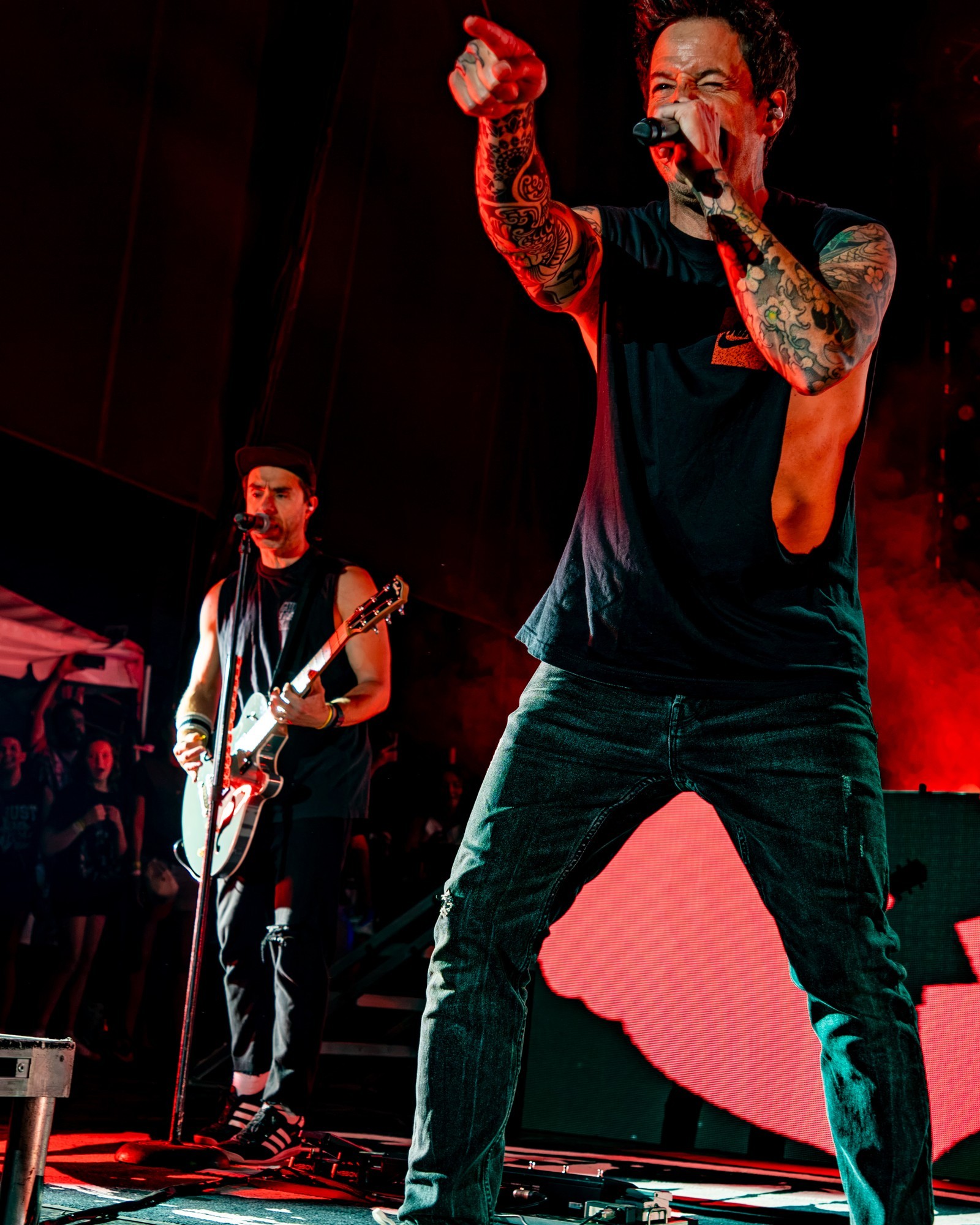 Simple Plan vocalist singing beneath red lights.