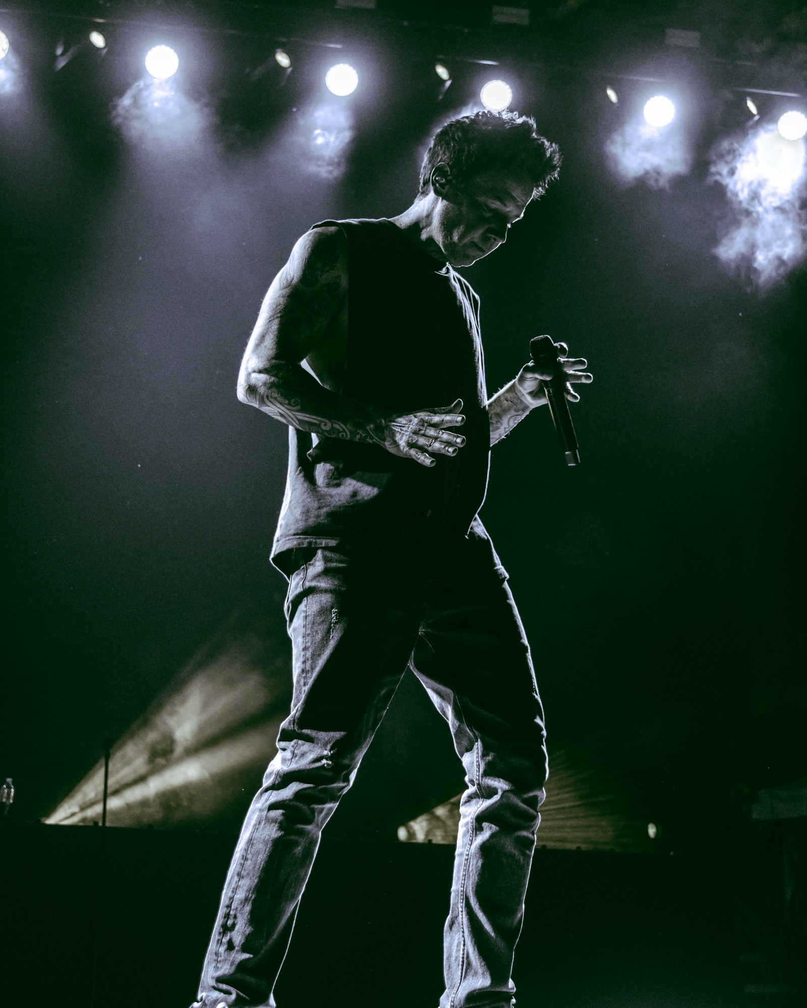 Simple Plan guitarist silhouetted beneath green and white lights.